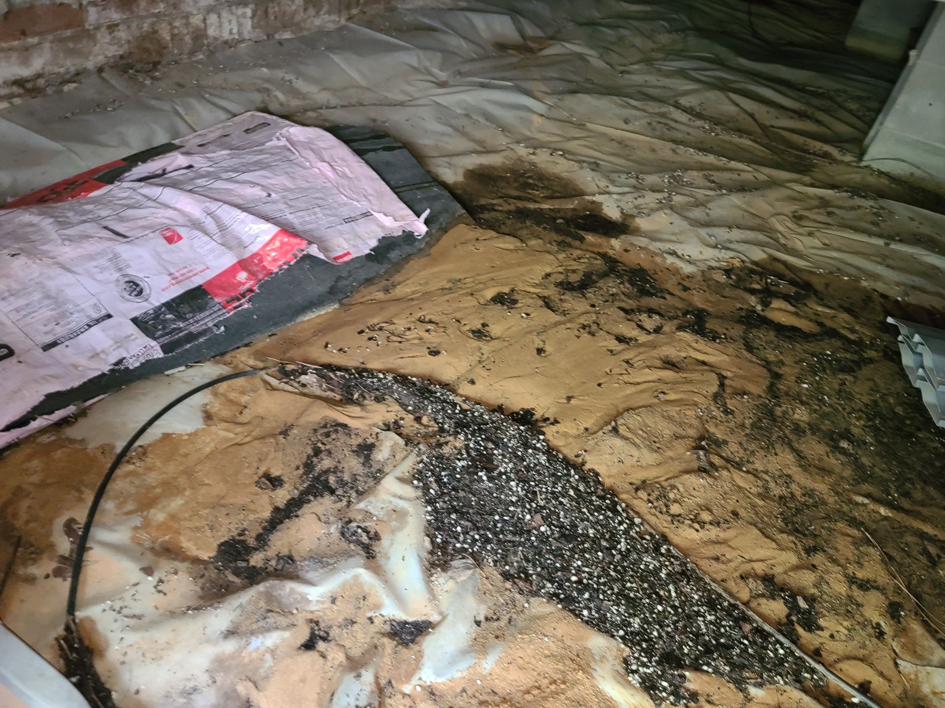 Flooded room with muddy water, debris, and a torn tarp on the floor