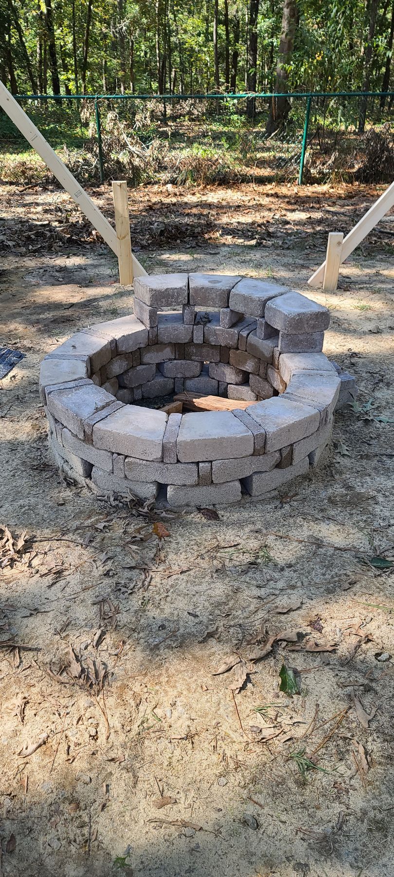 Stone fire pit with stacked bricks in a wooded outdoor yard