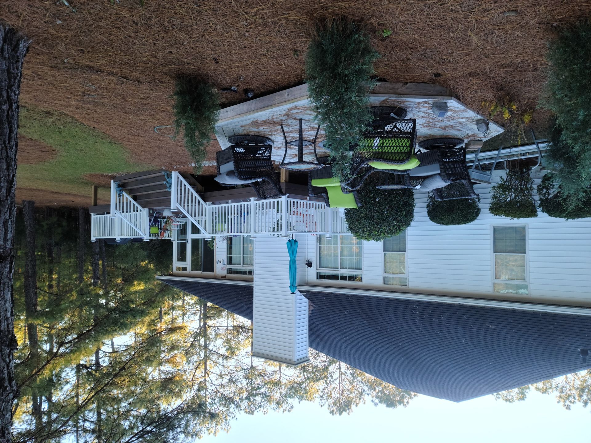 Upside-down view of a suburban house with white porch, parked car, and trees in a yard.