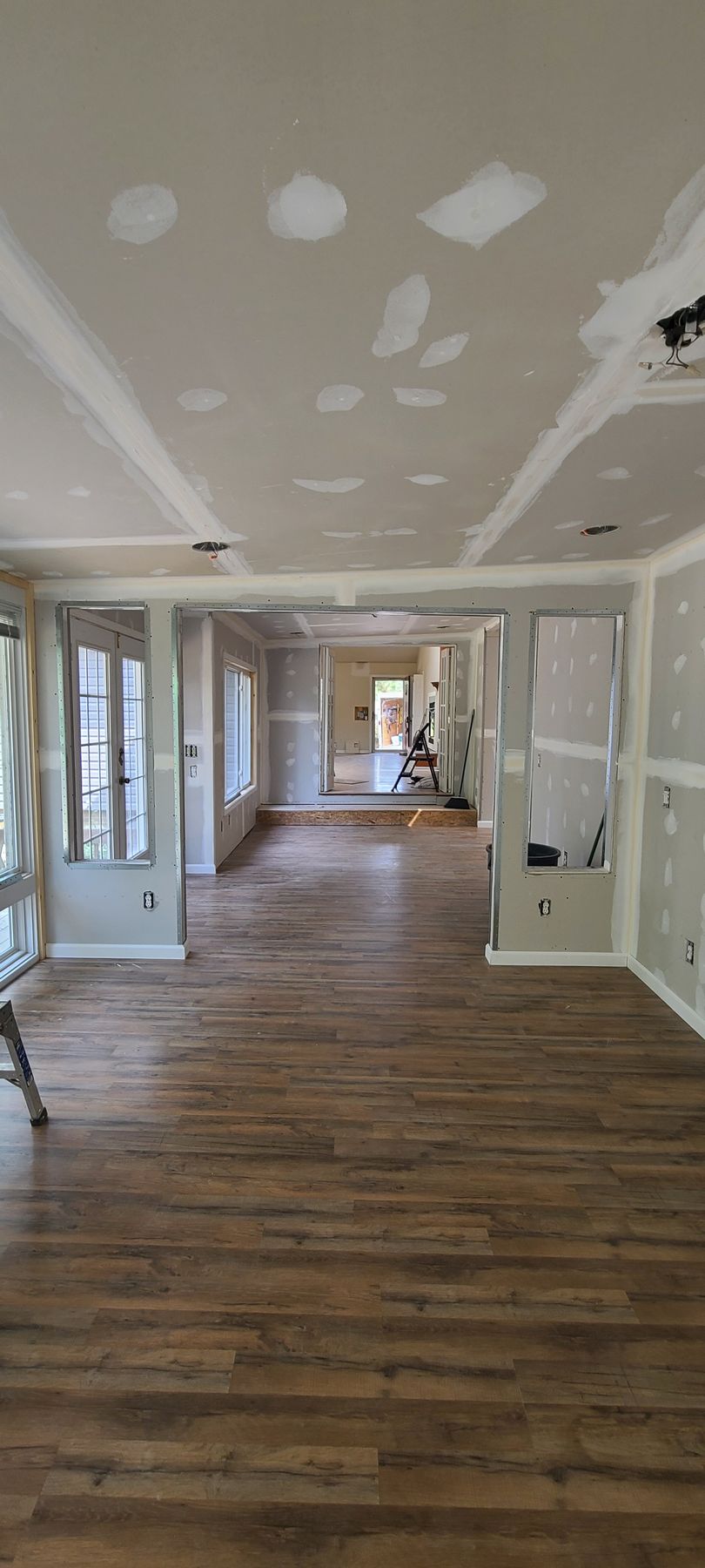 Empty hallway under construction with white drywall and wood flooring, view down a long corridor