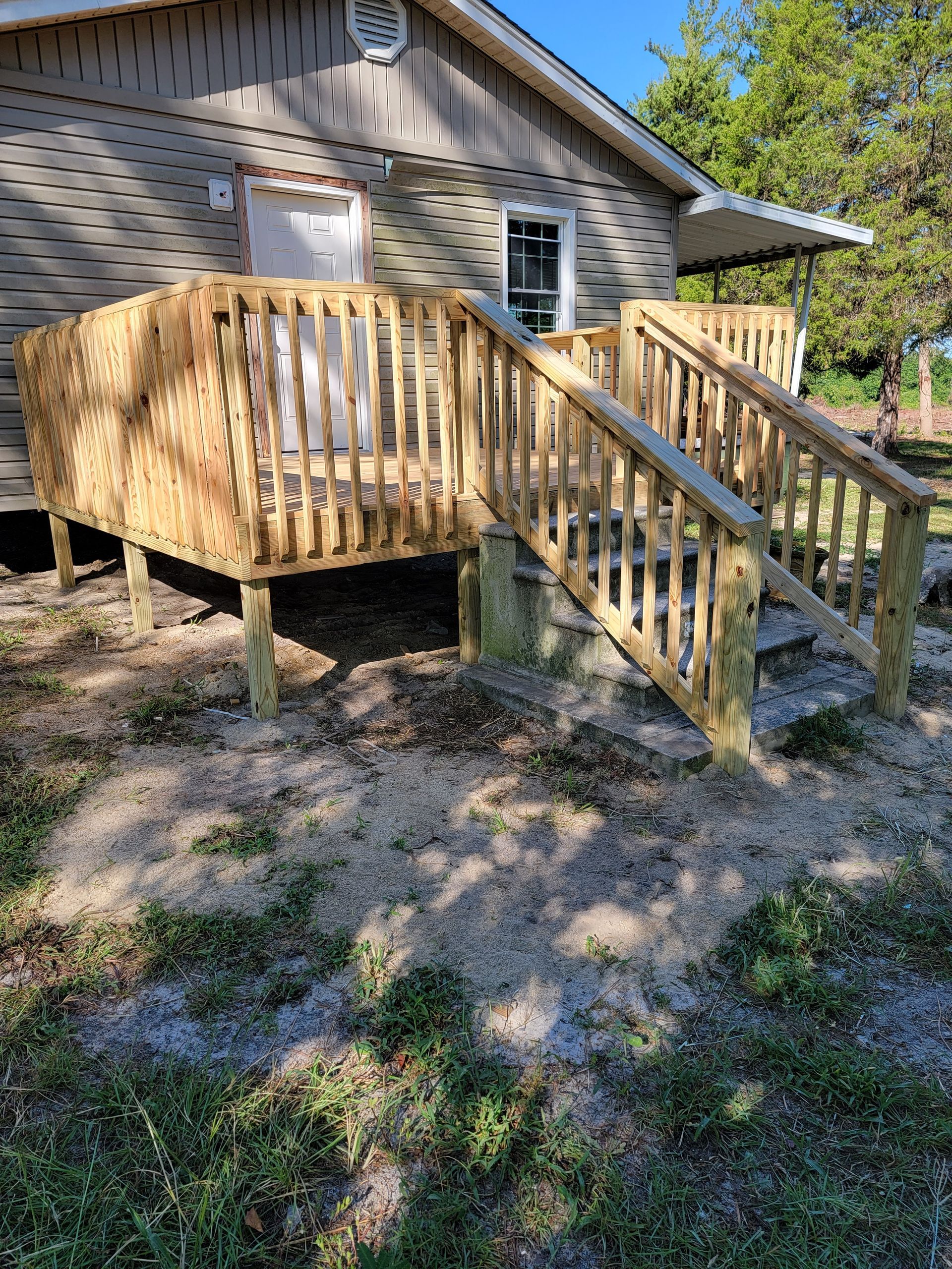 Wooden wheelchair ramp and deck outside a house with stairs and railings