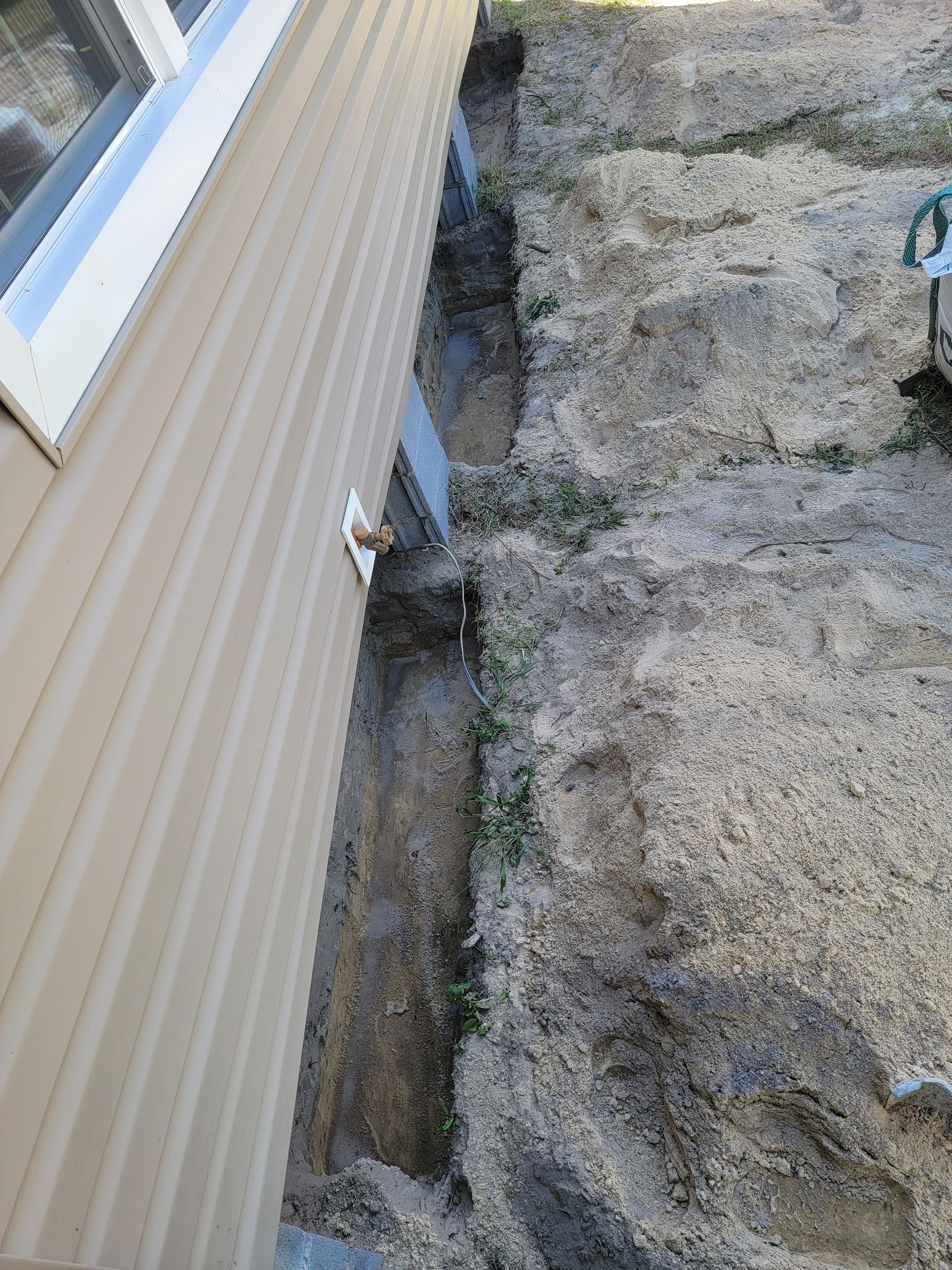 Side of beige house beside large gray rock face with a narrow gap between them