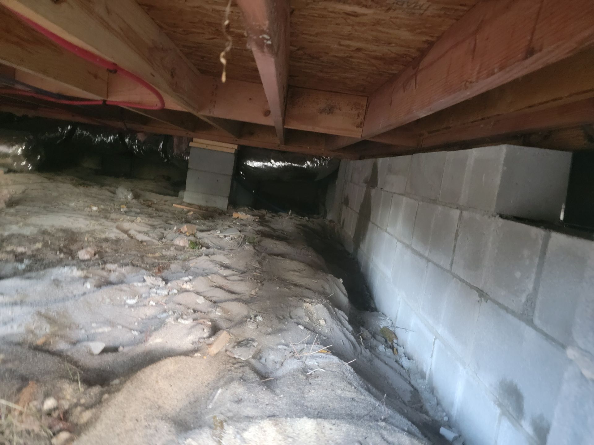 Crawlspace under a house with exposed insulation and cinder block foundation walls