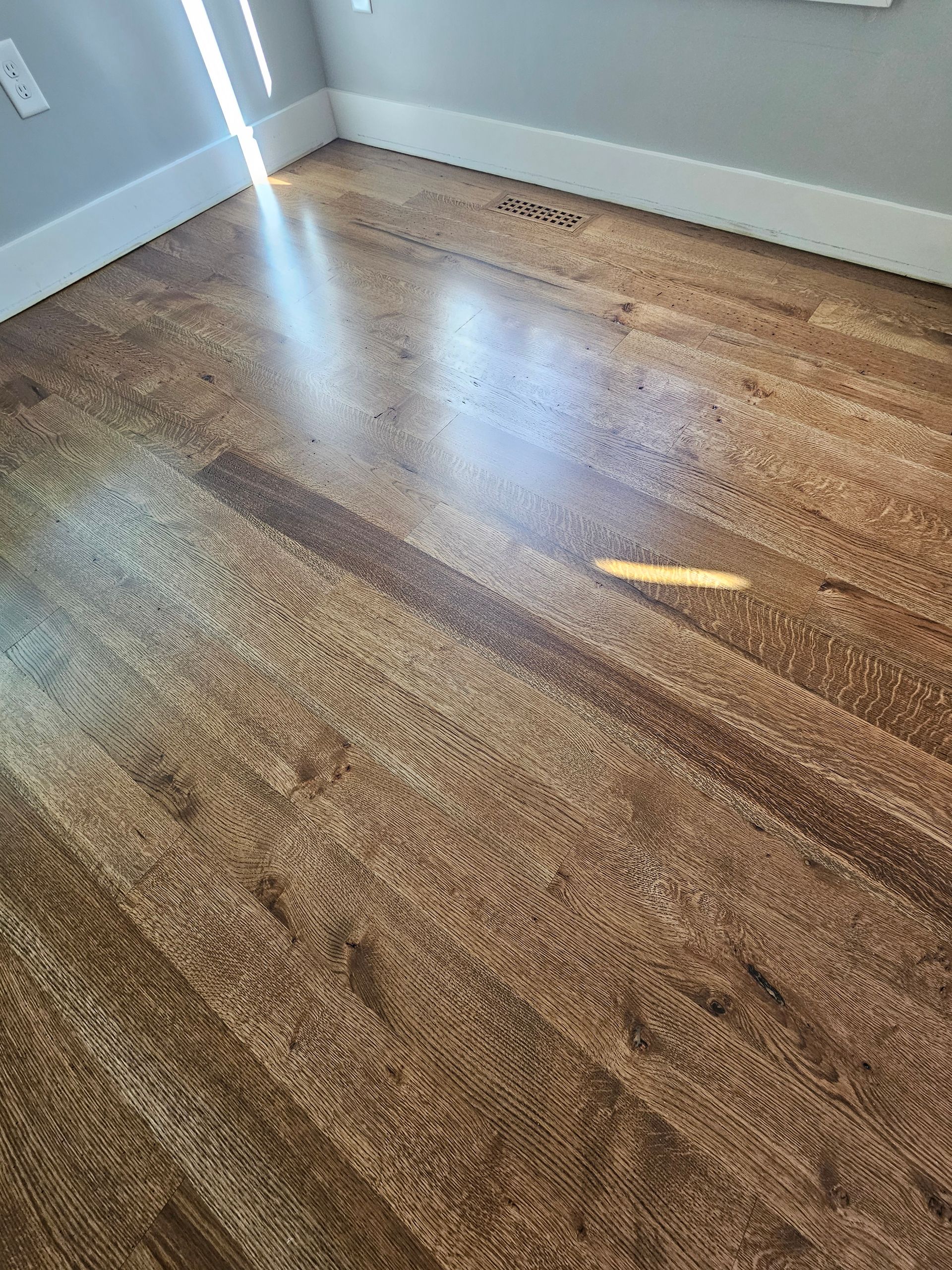 Empty carpeted room with light gray walls and a bright sunlit patch on the floor