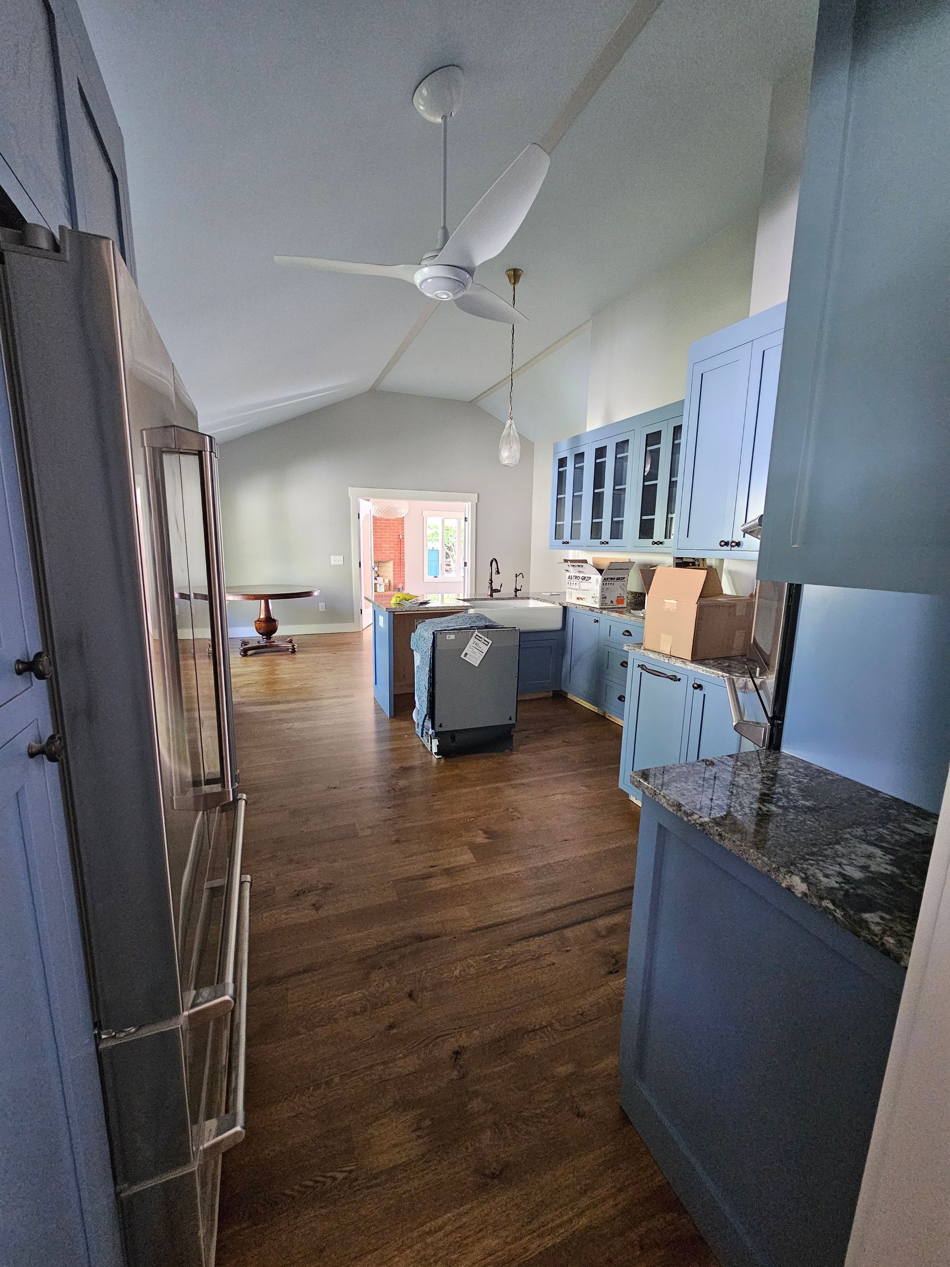 Bright kitchen with wood floors, blue cabinets, and a large ceiling fan.