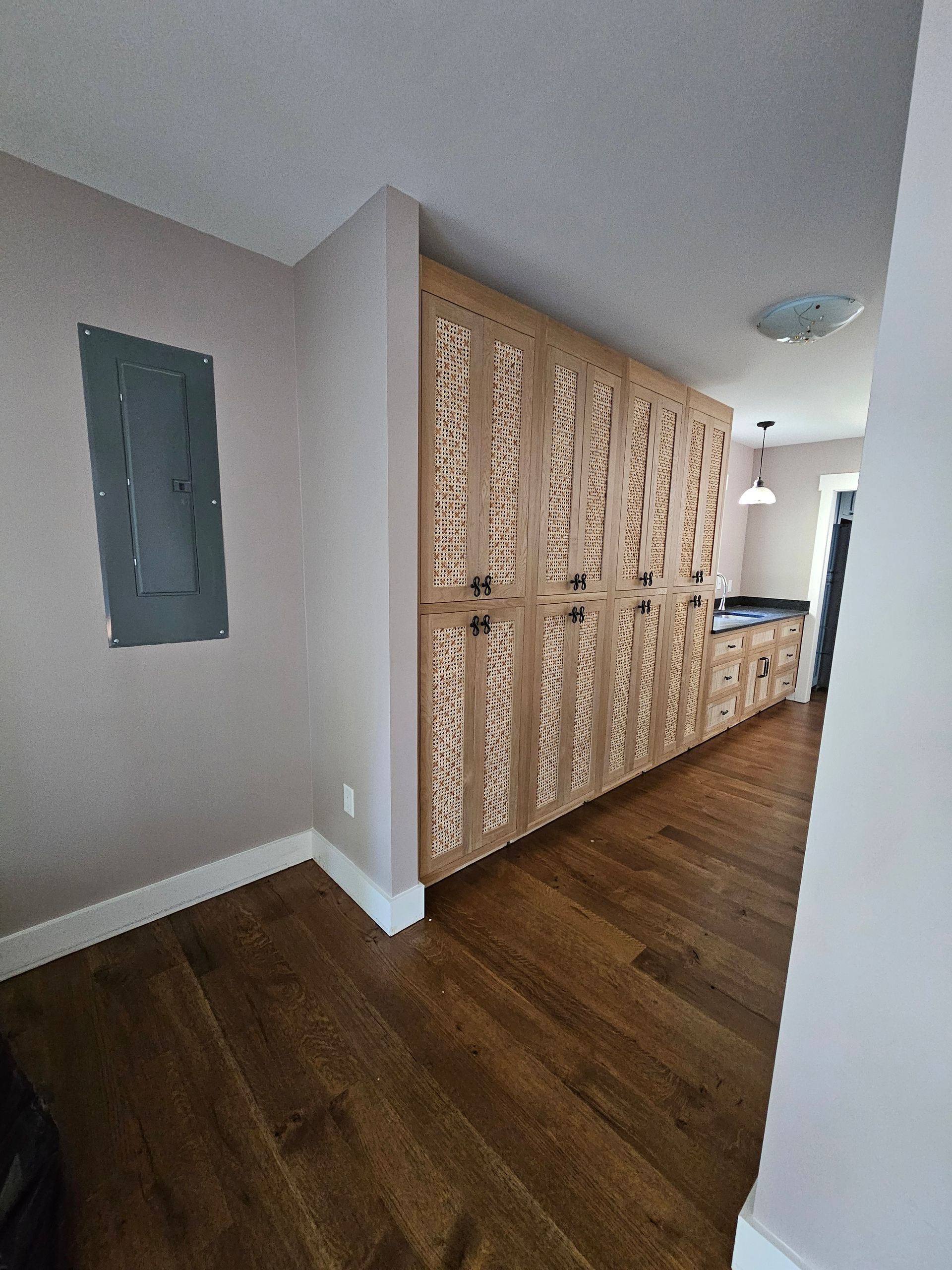 Hallway with wood floor, decorative wooden room divider, and electrical panel on the left.