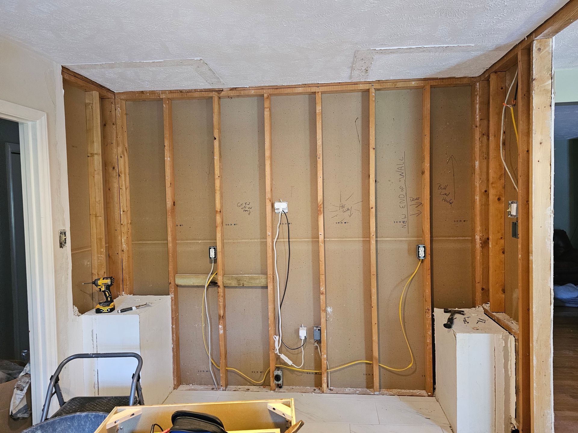 Partially demolished room with exposed wall studs, wiring, and debris during renovation