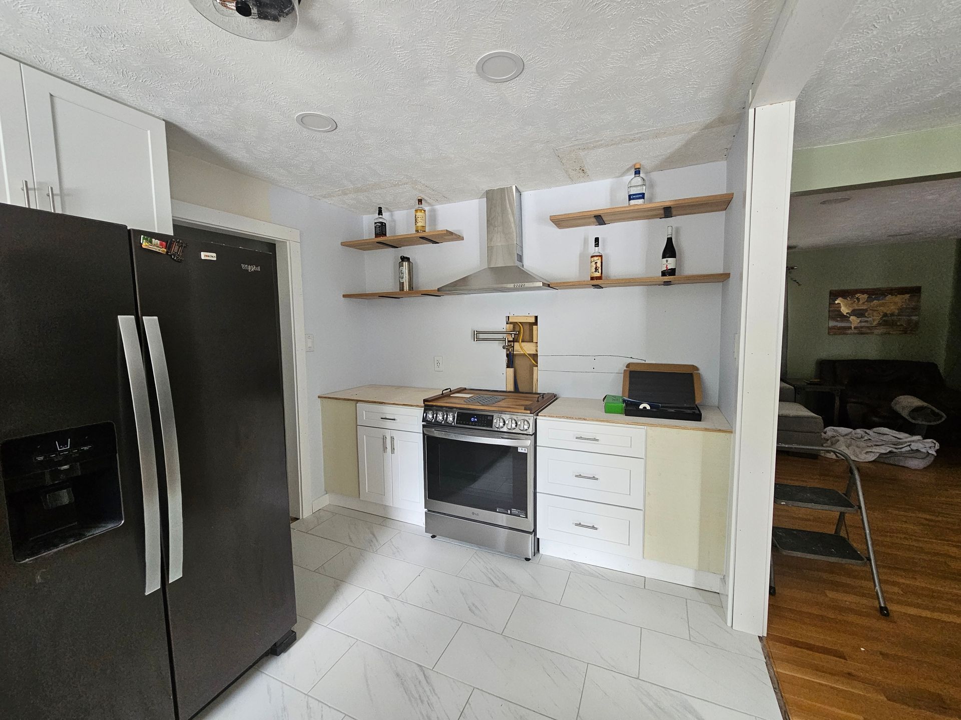 Modern kitchen with black refrigerator, white cabinets, open shelves, and stainless stove