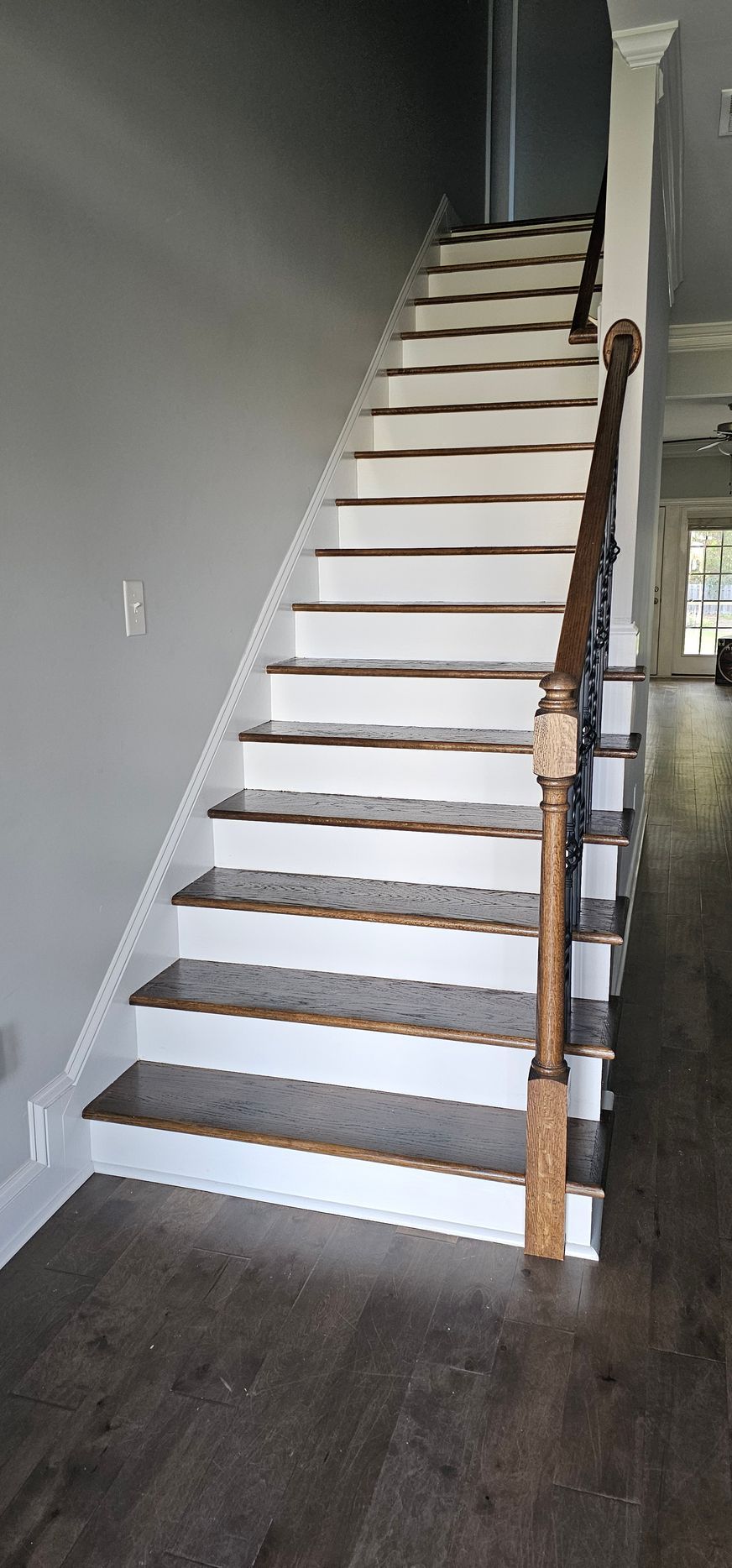 Indoor staircase with white risers and wooden treads in a gray hallway