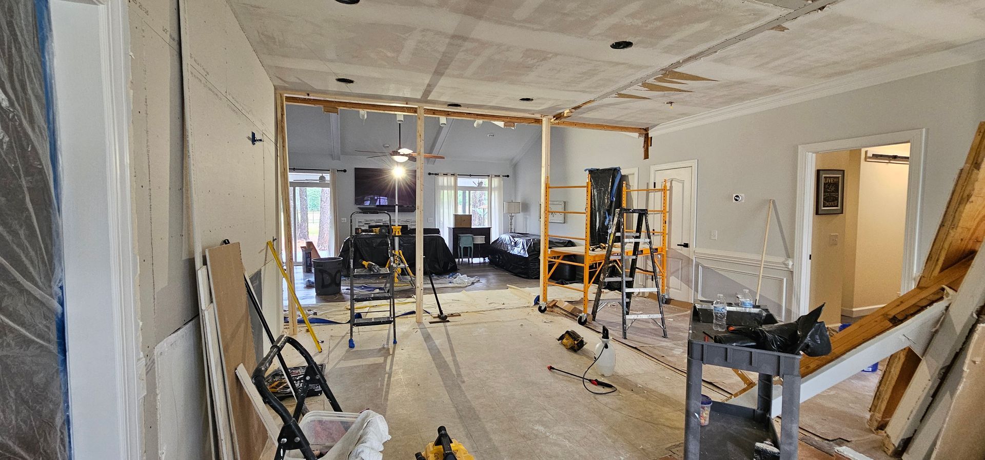 Partially renovated room with exposed wiring, tools, and construction materials scattered around.
