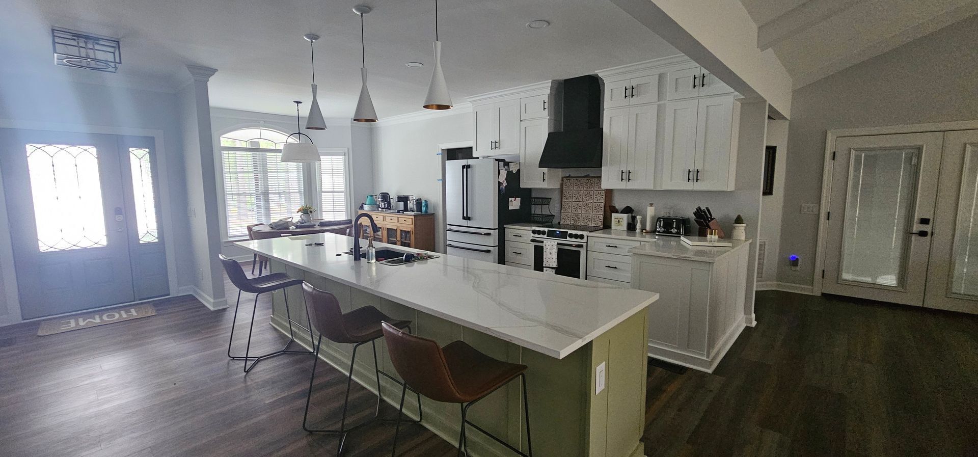 Bright kitchen with white cabinets, island seating, hardwood floors, and large windows