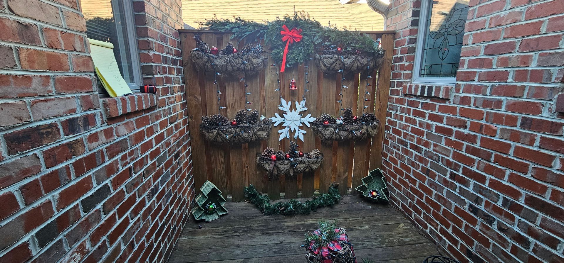 Brick courtyard with a wooden memorial wall covered in flowers and hanging decorations