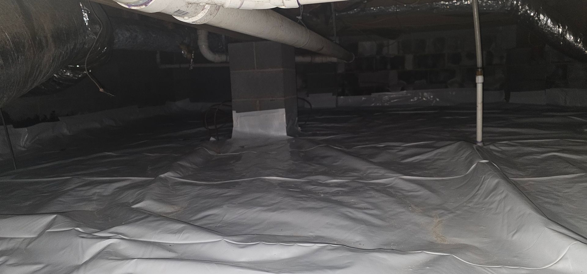 Covered outdoor patio with a large gray tarp spread across the floor and a post on the right