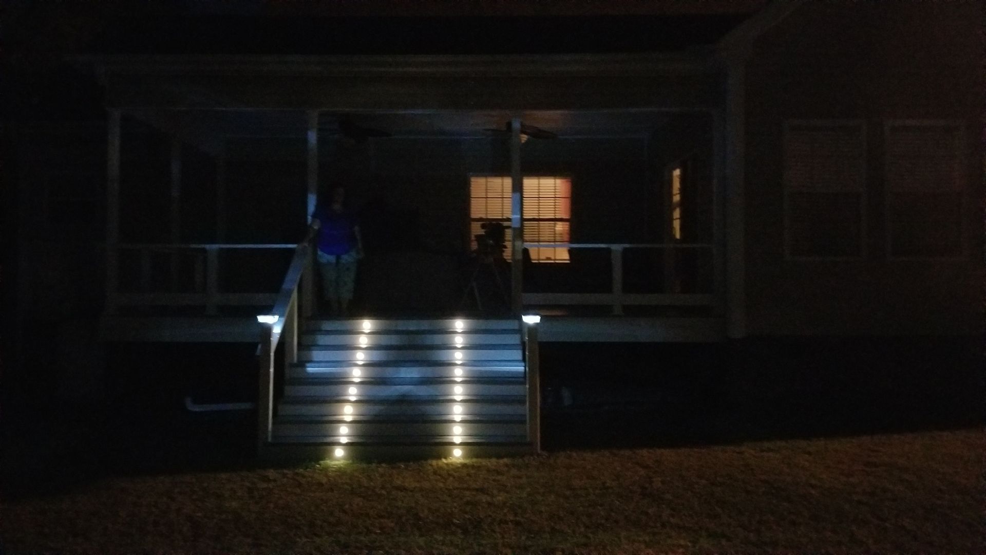Dimly lit building entrance with illuminated stairs leading to a doorway at night