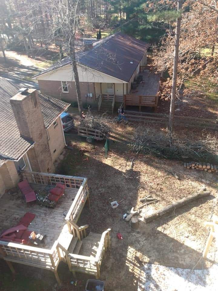 Aerial view of a house with a deck, chimney, and wooded yard in autumn.