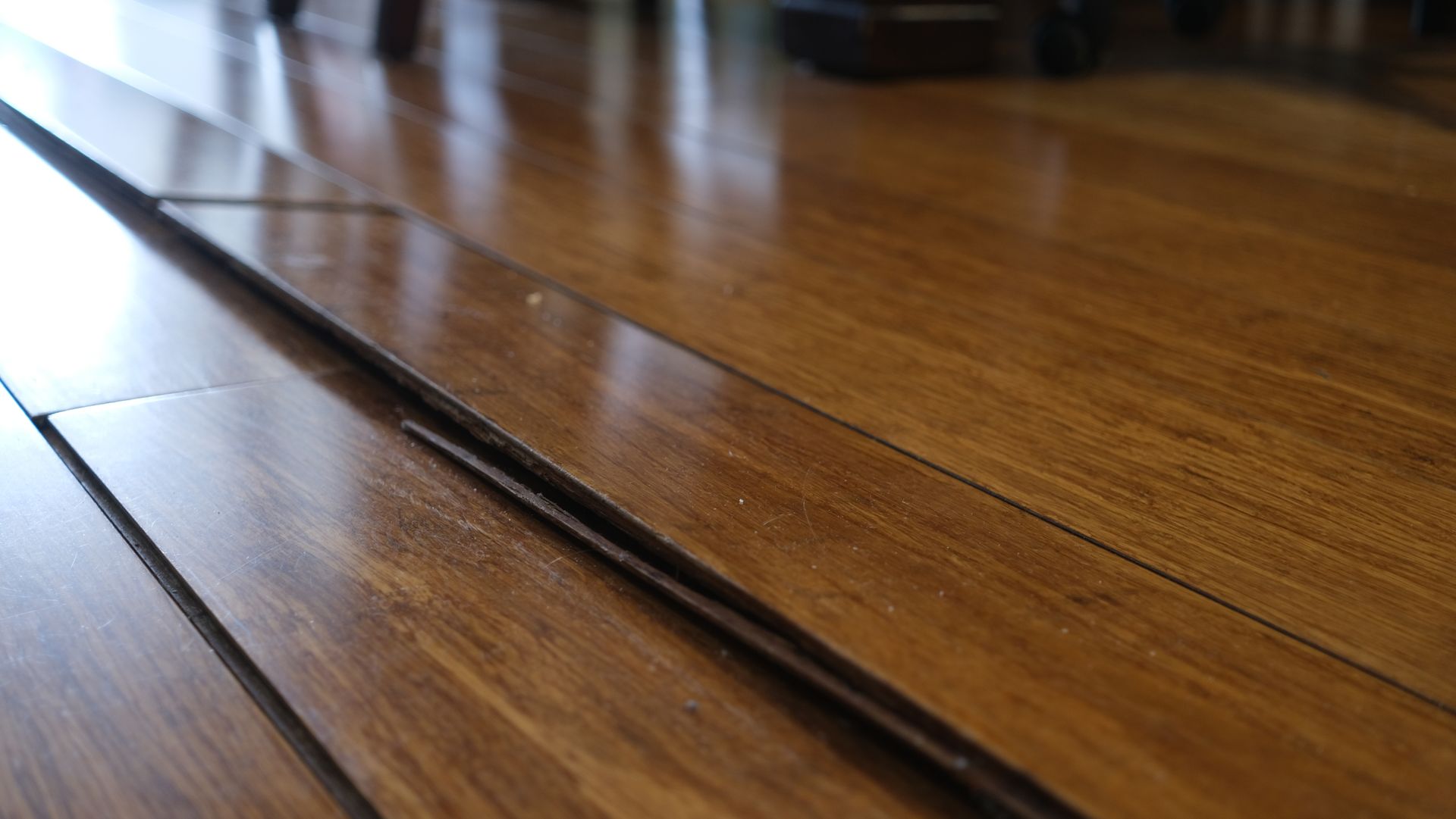 Close-up of a wooden floor with a visible seam and reflections of light.