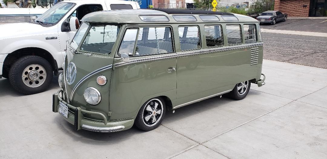 A green van is parked in a parking lot next to a white truck.