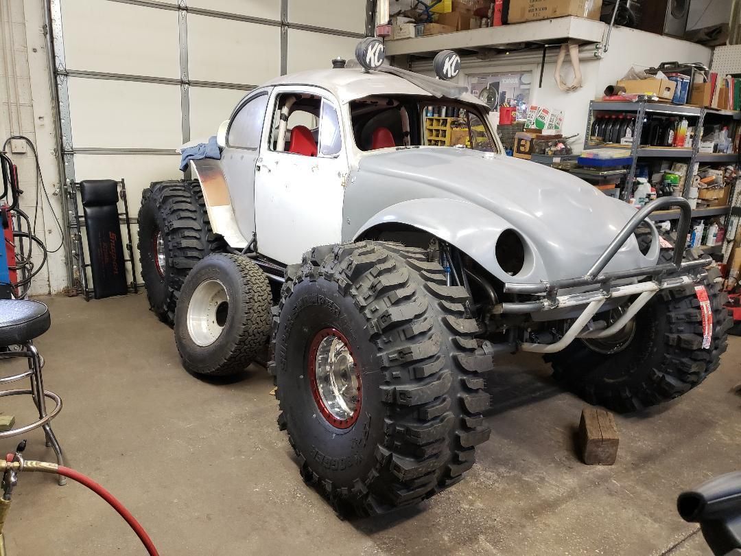 A monster truck is parked in a garage next to a garage door.