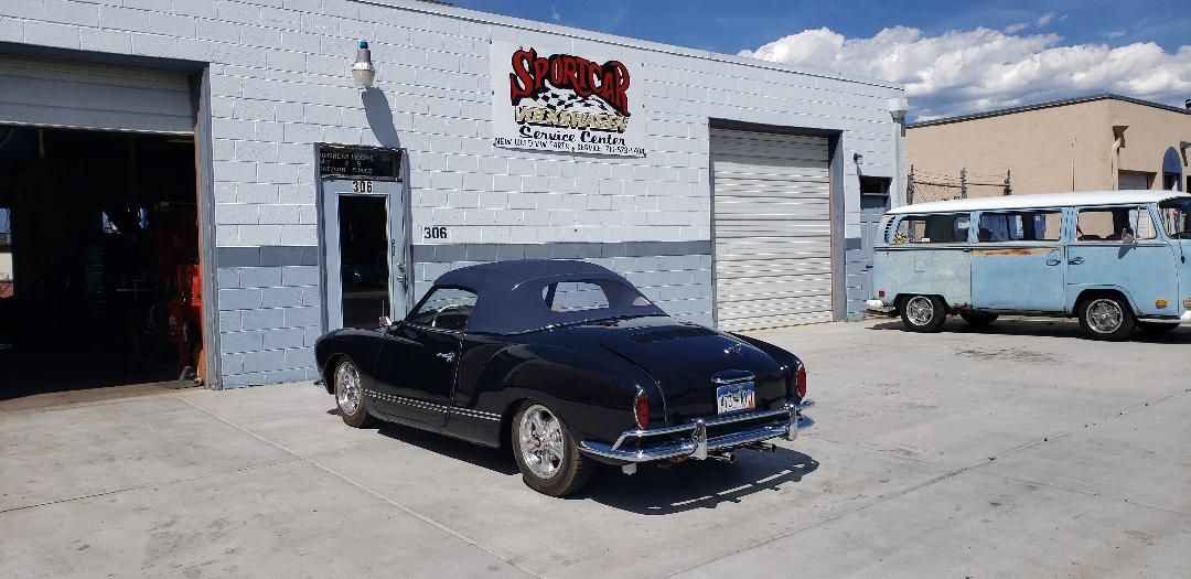 A black car is parked in front of a building.