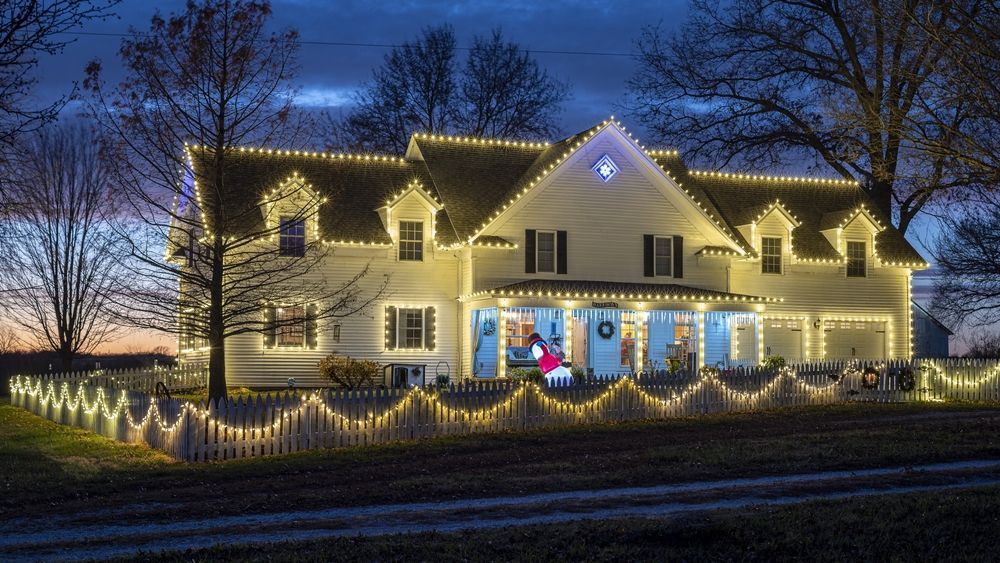 A large house is decorated with christmas lights at night.