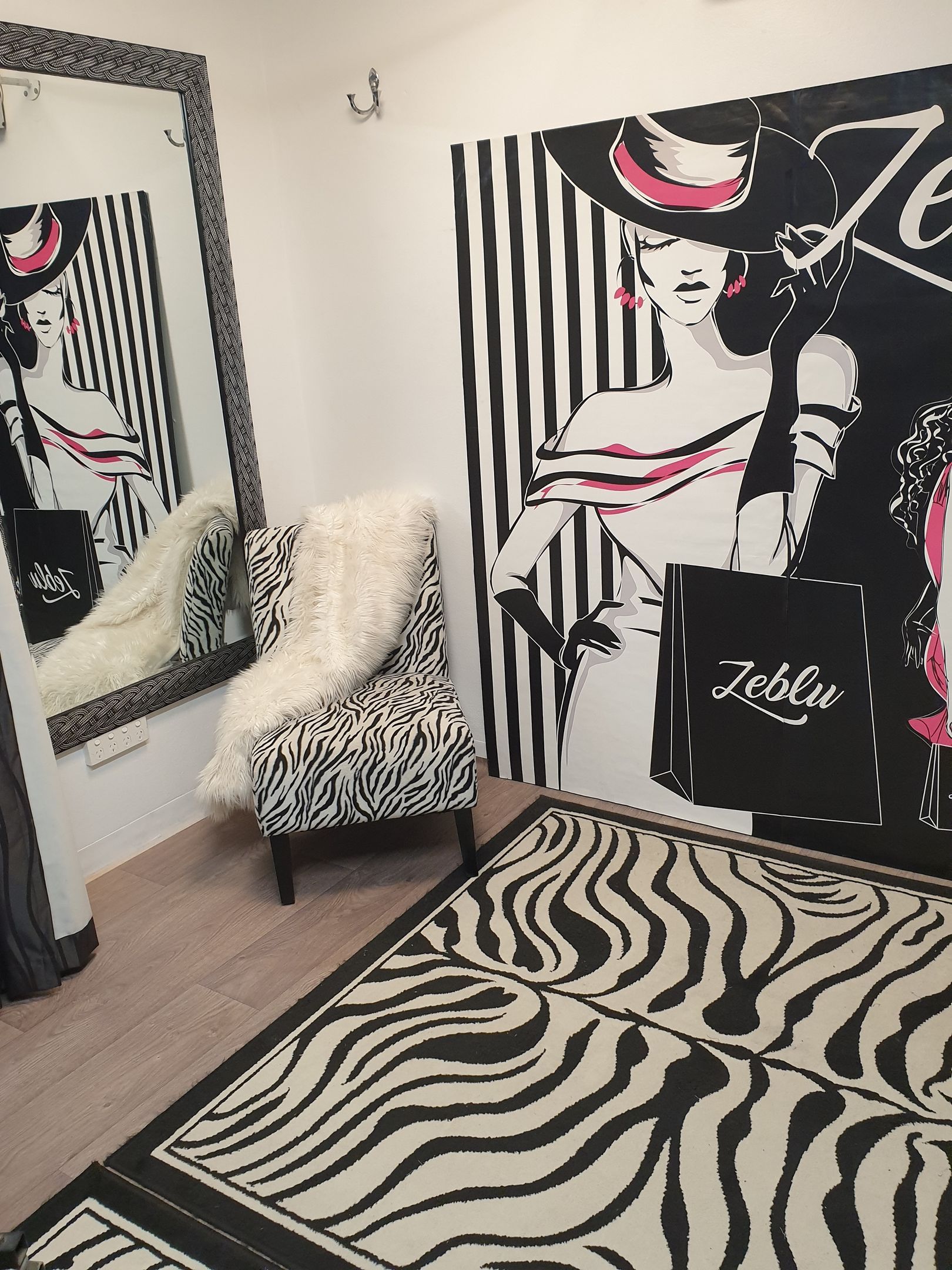 Zebra print room with fashion artwork on wall and rug, a decorative chair, and a large mirror.