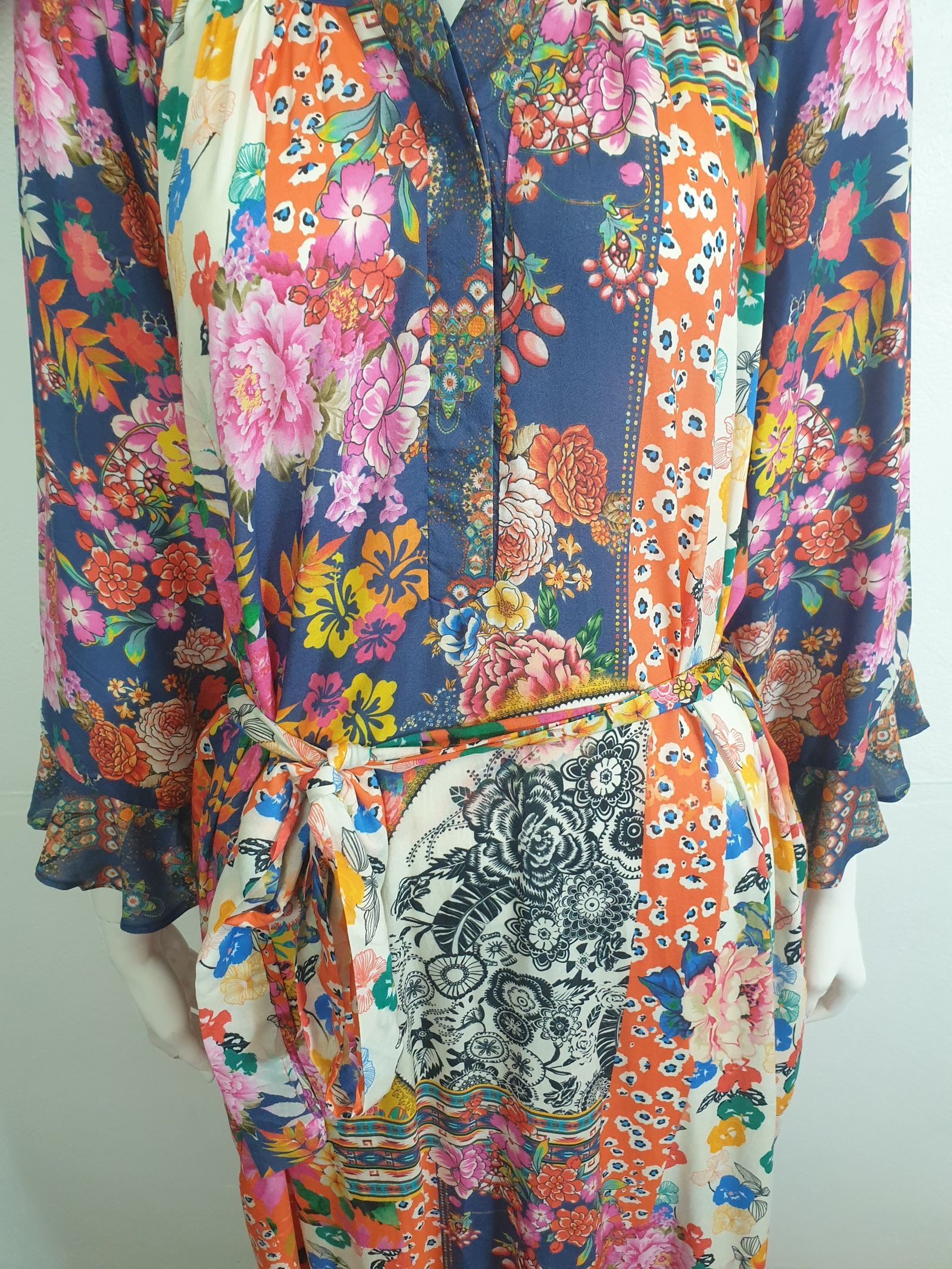 Woman in a colorful floral print dress with a navy blue bodice and a matching belt.
