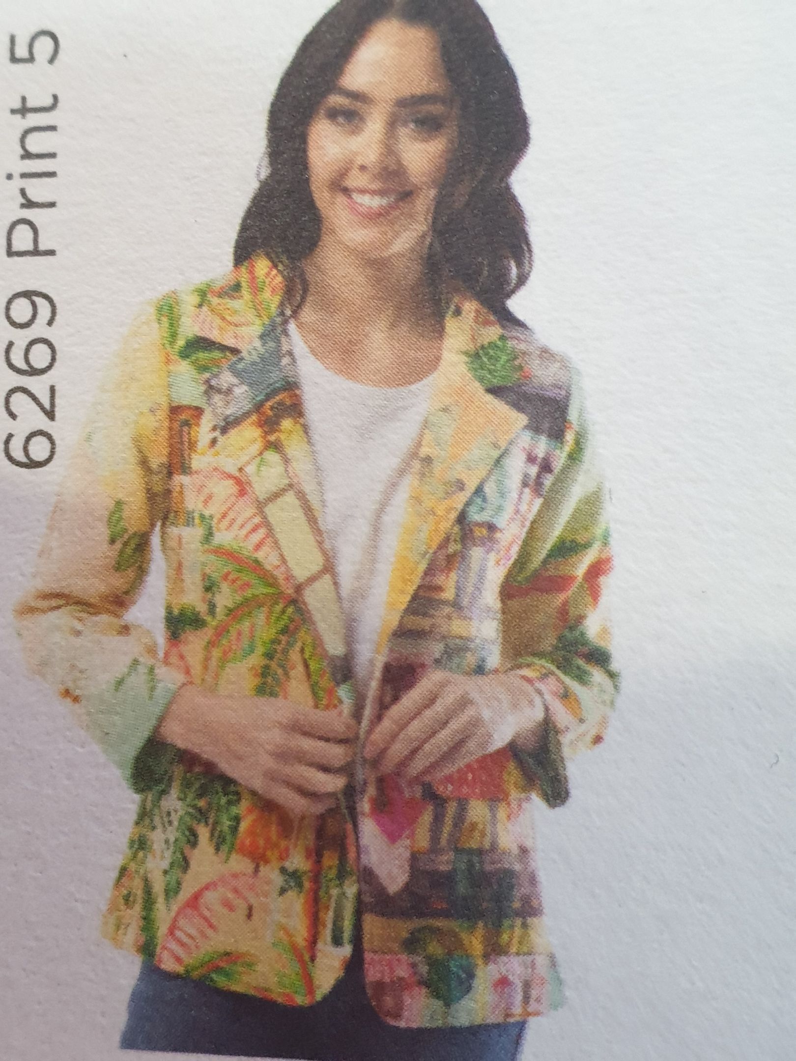 Woman wearing a colorful patterned blazer, smiling, indoors.