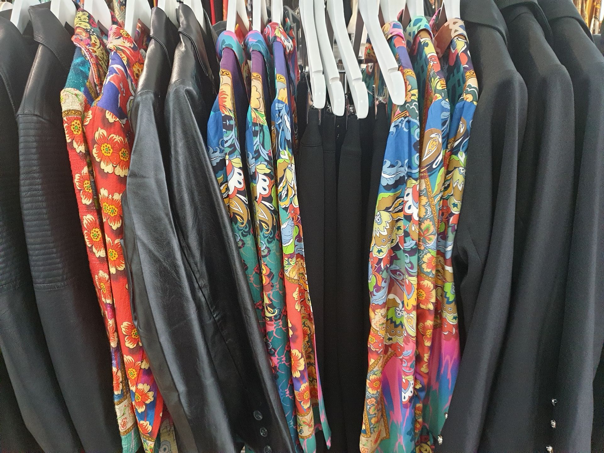 Clothes rack with patterned tops and solid black jackets.