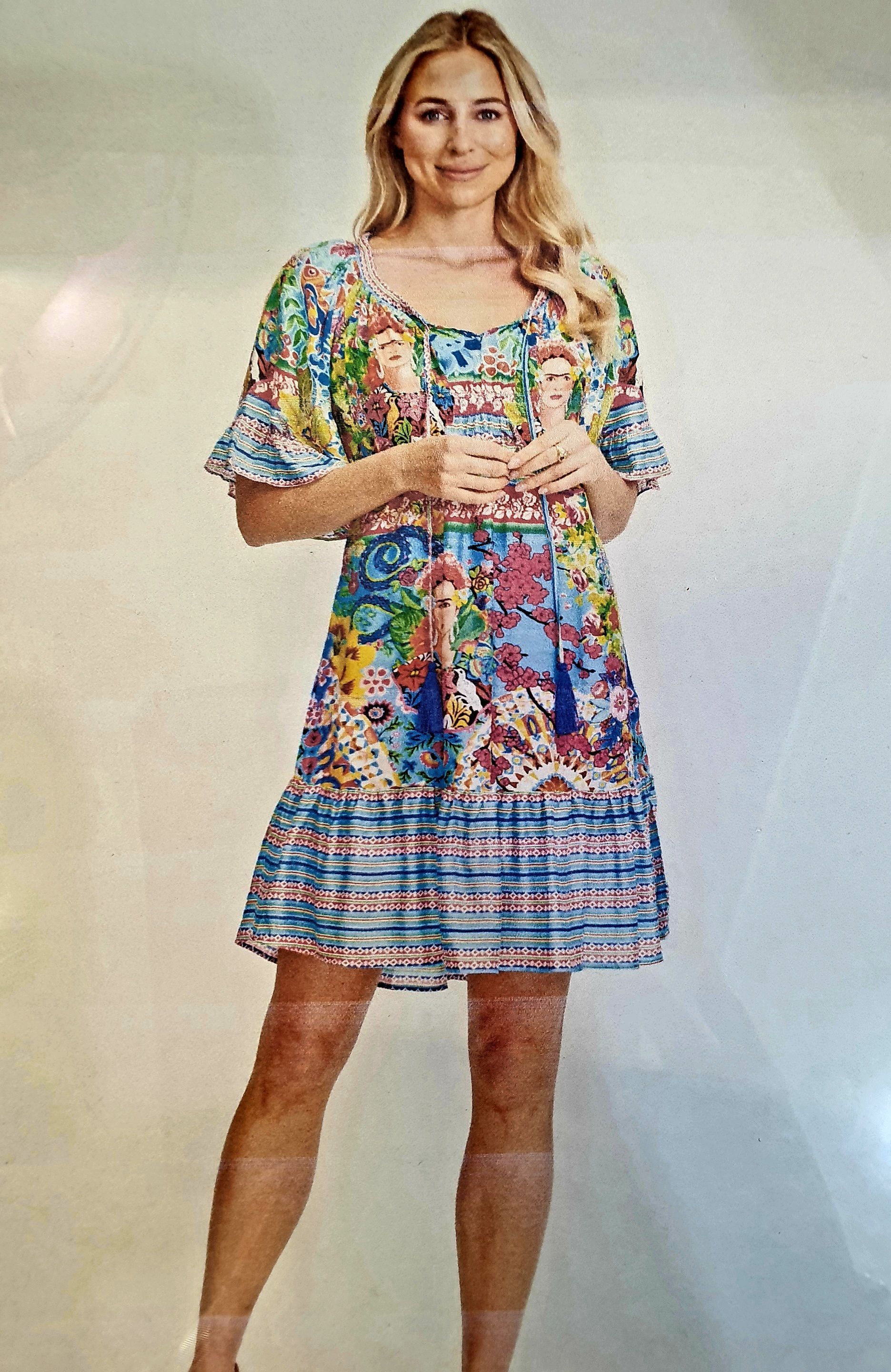 Woman in a colorful floral dress, smiling, standing.