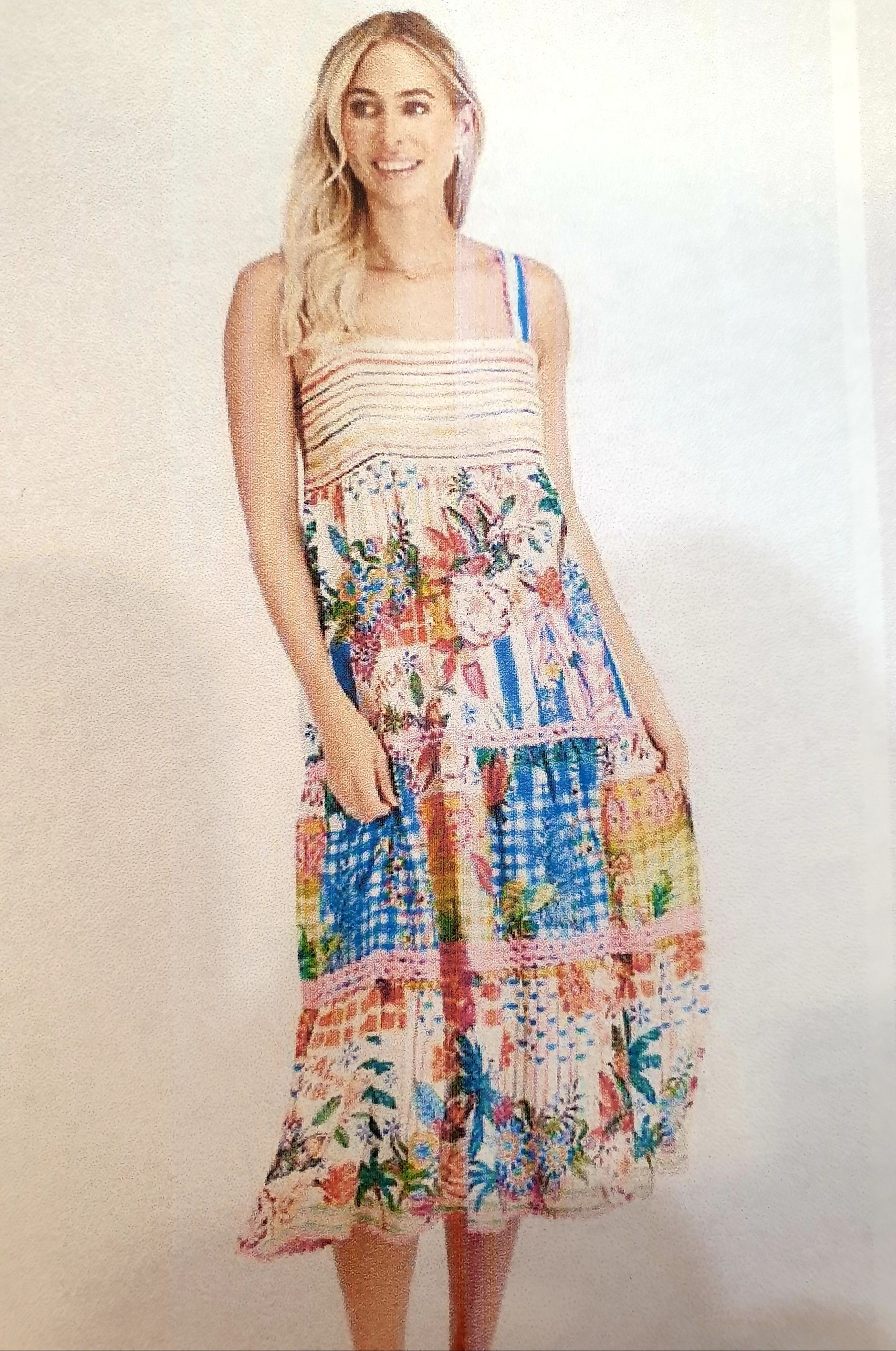 Woman in a colorful floral summer dress, smiling, standing.