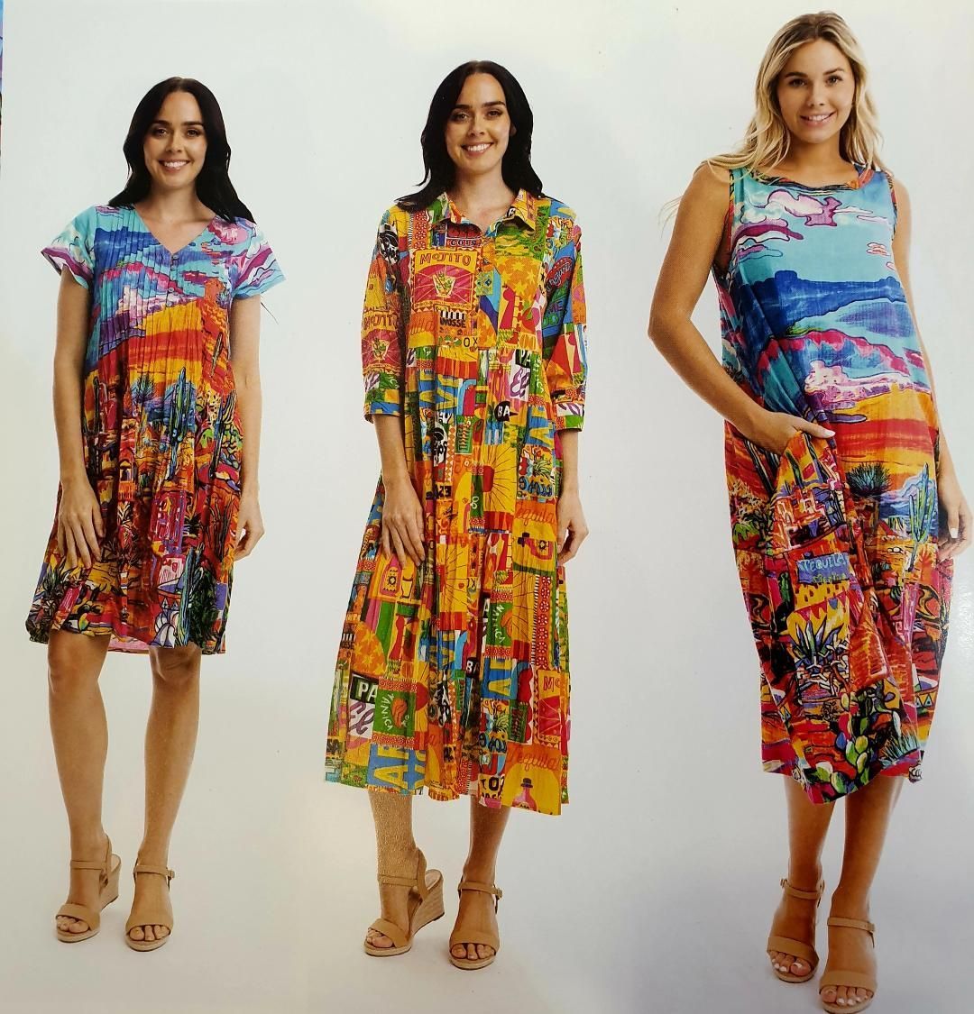 Three women in colorful, patterned dresses, each wearing sandals, posing in a studio.
