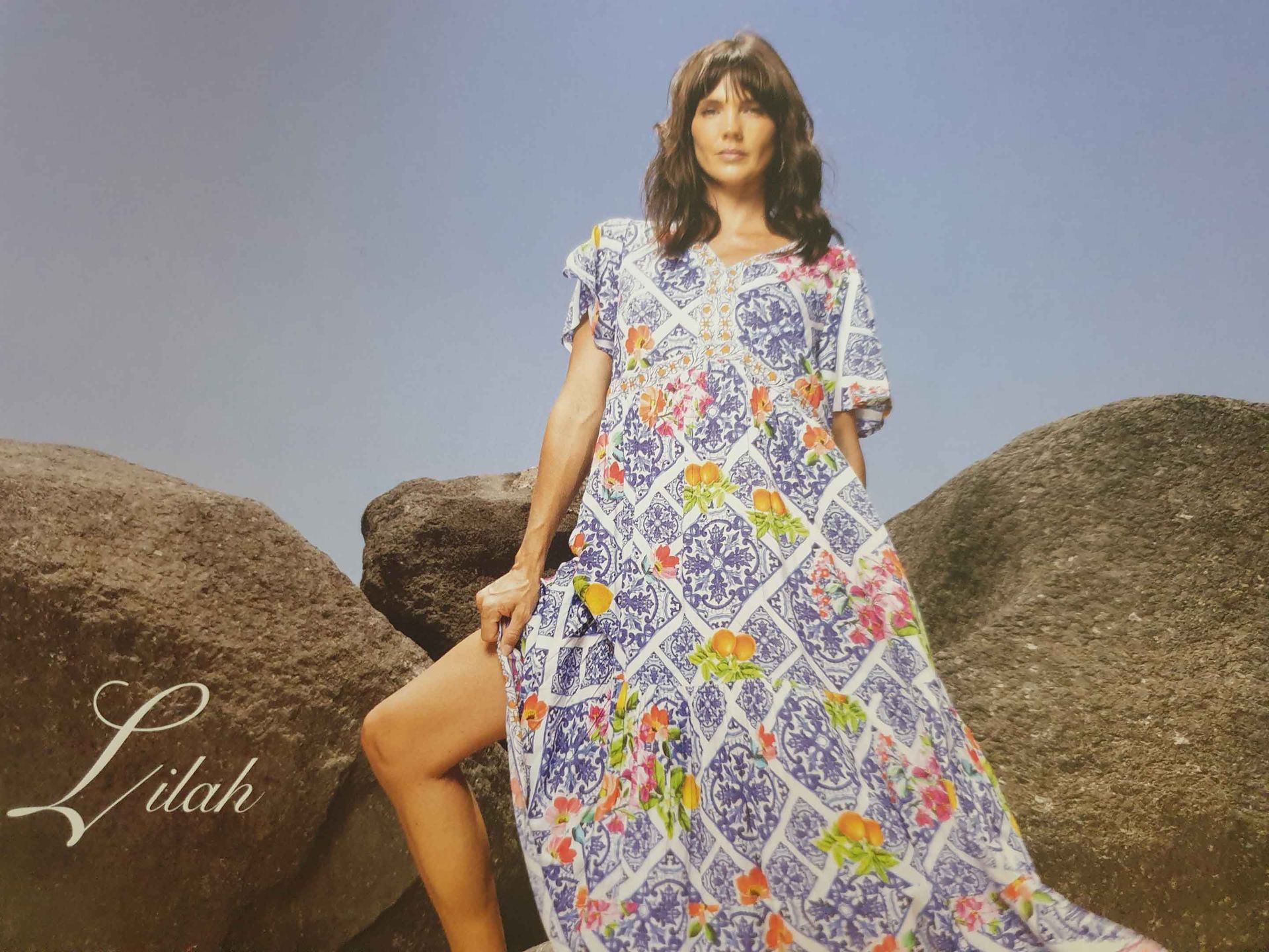 Woman in floral dress posing on rocks.