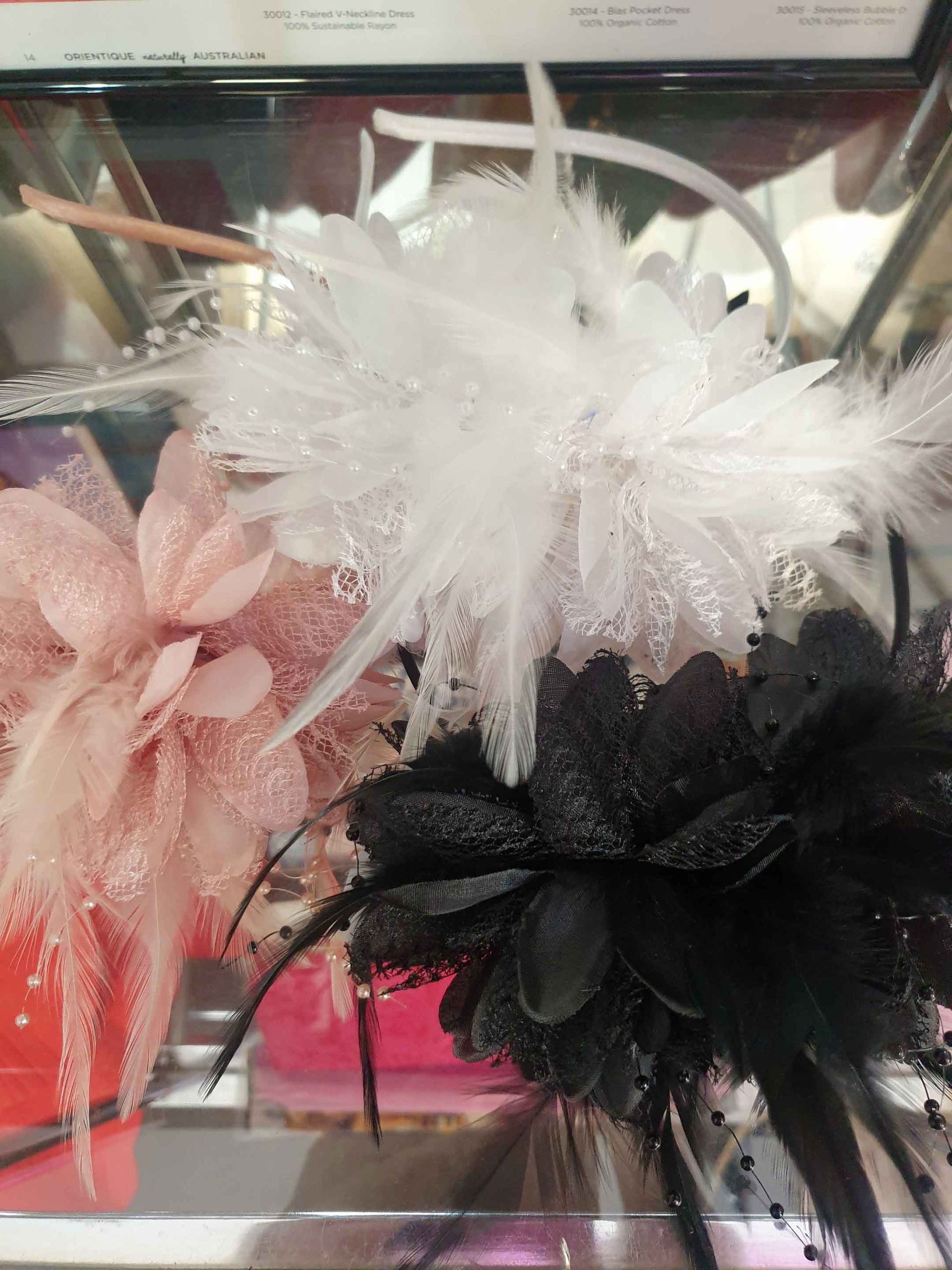Headbands with pink, white, and black feathered flowers displayed in a store.