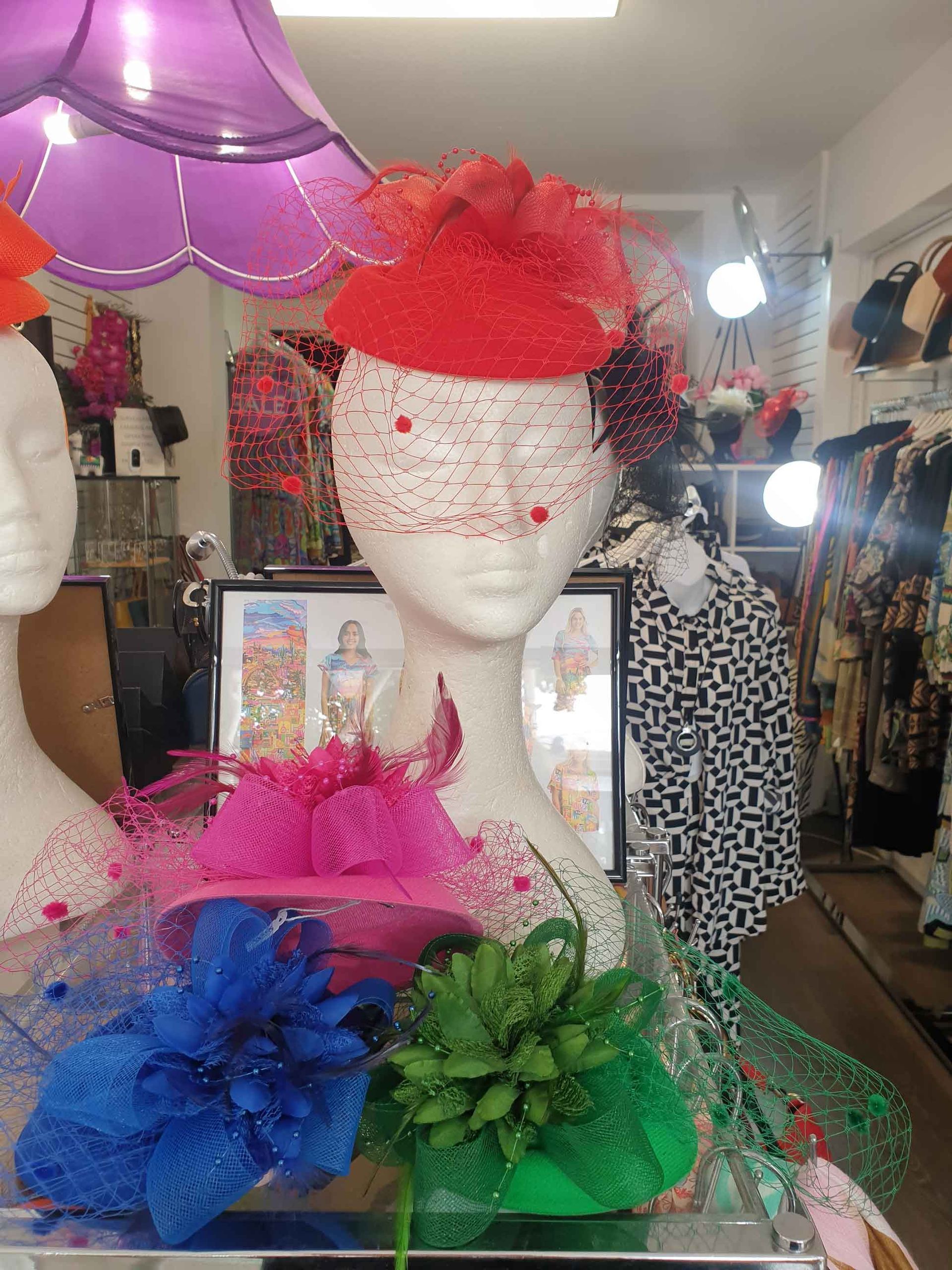 Mannequin heads displaying colorful hats in a shop window.
