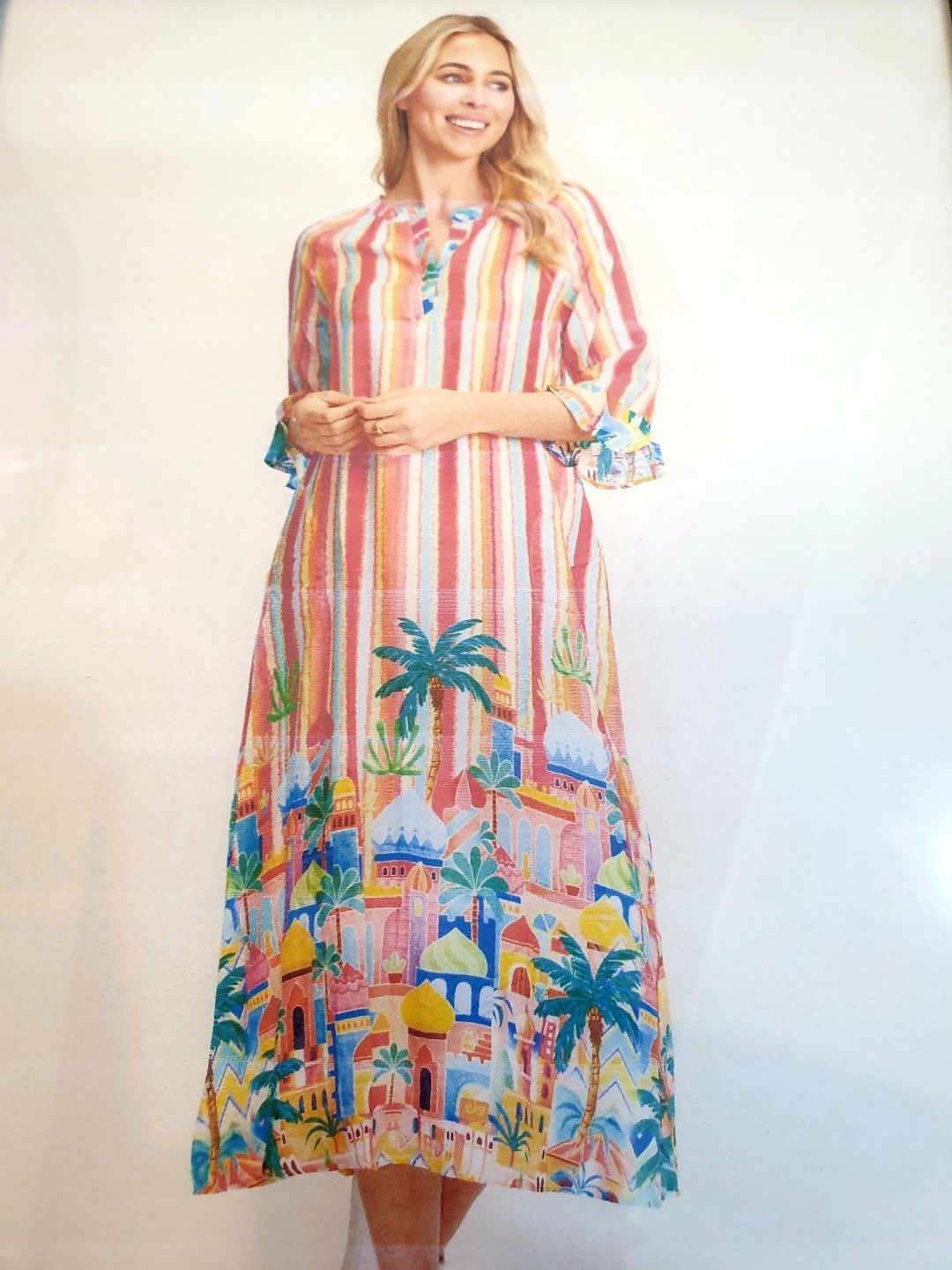 Woman in colorful striped dress with palm tree and building print.