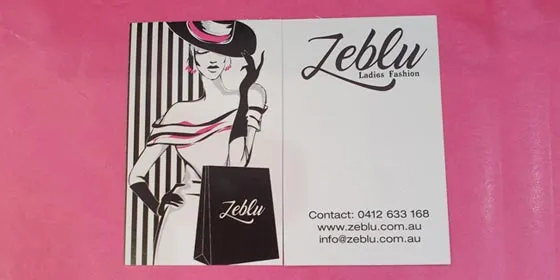 Business card for Zeblu, a ladies fashion store. Illustrated woman with a shopping bag. Addresses, phone, and website included.