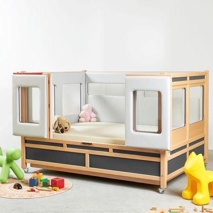 A child 's bed with a teddy bear on top of it.