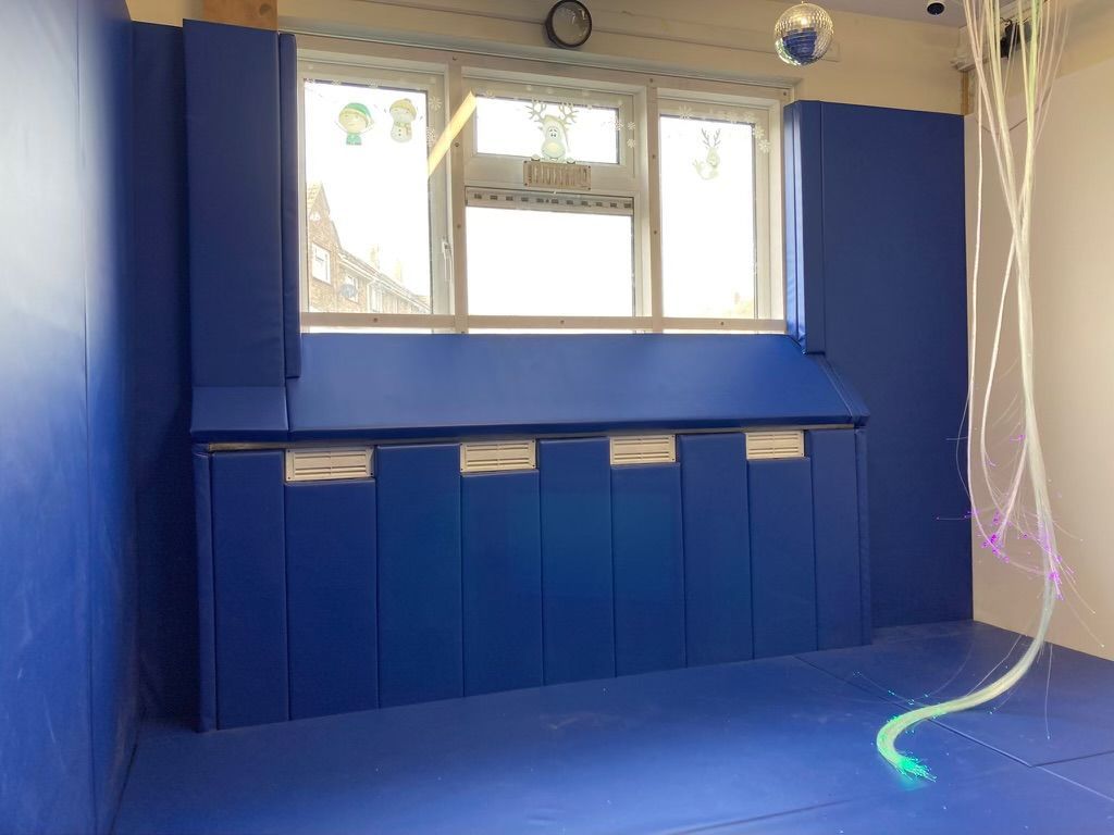 A padded room with blue walls, a blue floor and a window.