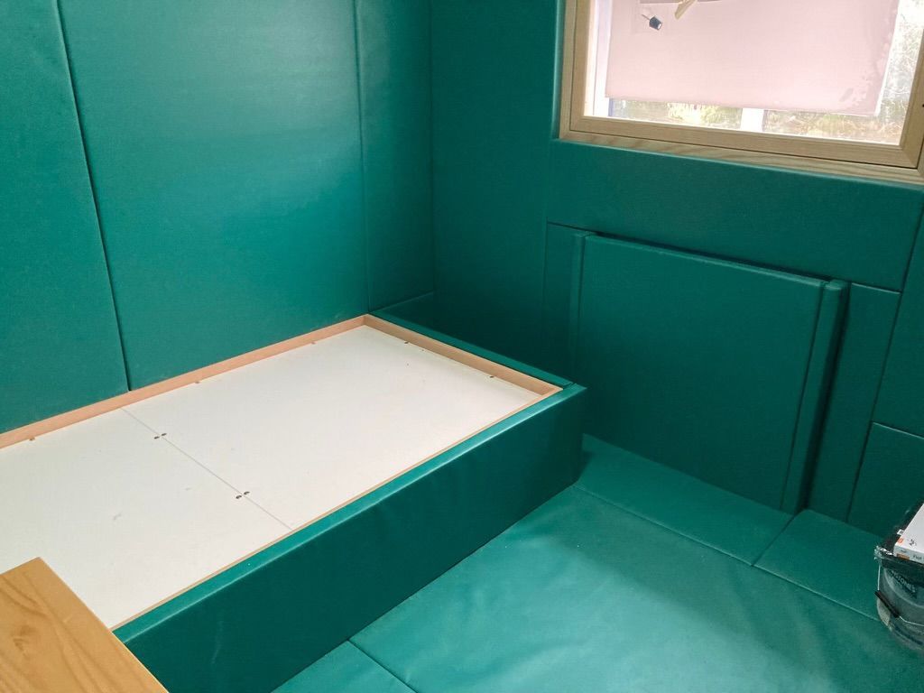 A padded bedroom with green walls