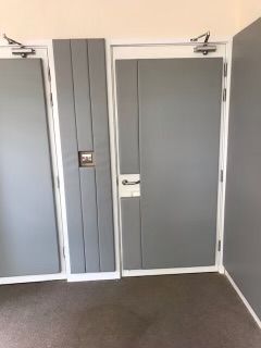 A padded room with two gray doors and a white door handle.