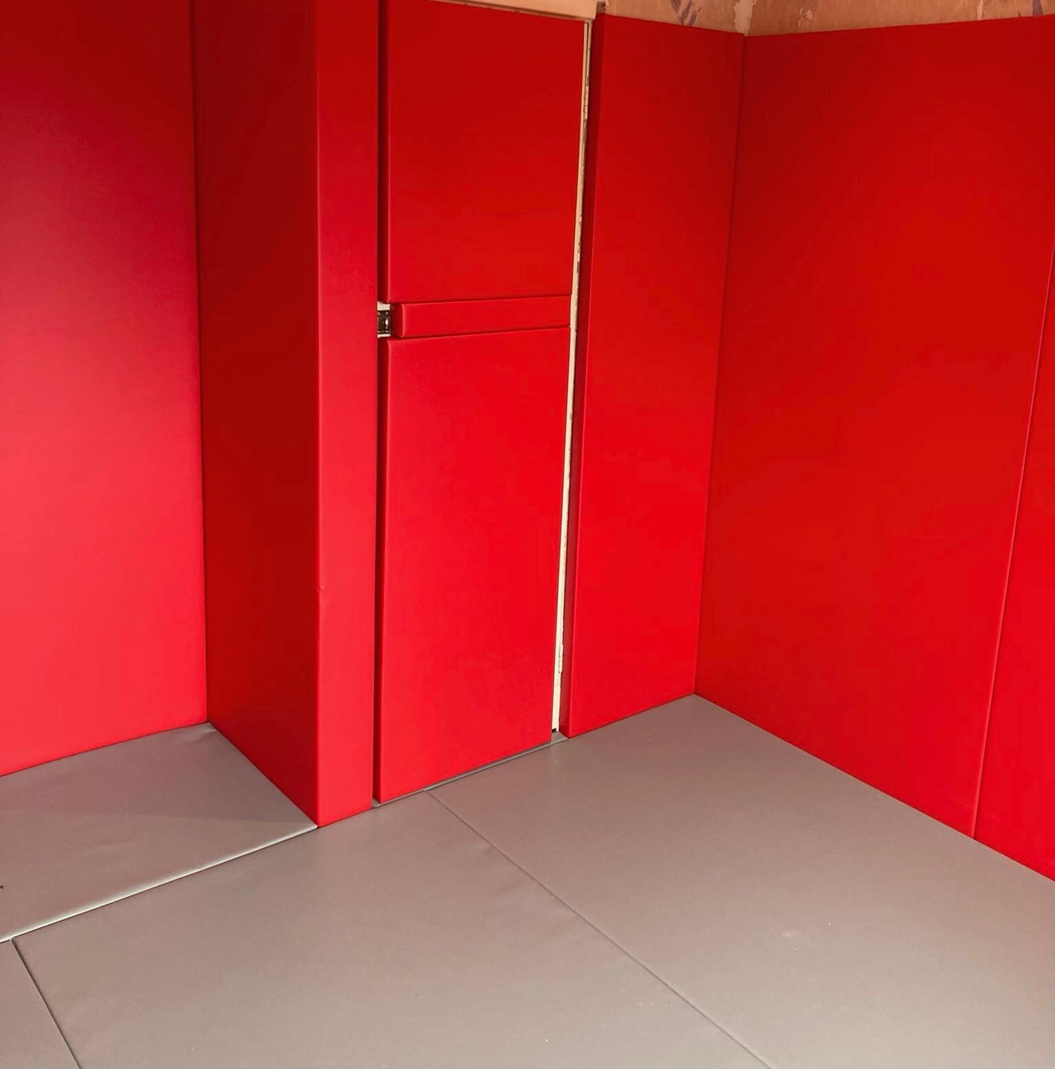 A padded room with red walls and a grey floor.