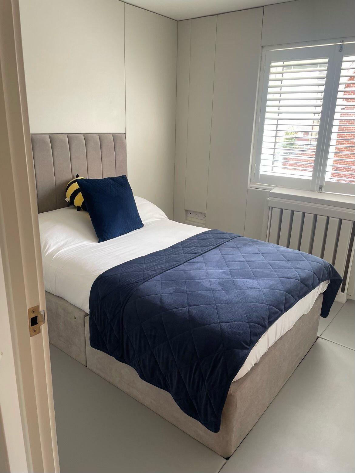 A padded bedroom with a bed and a window with blinds.