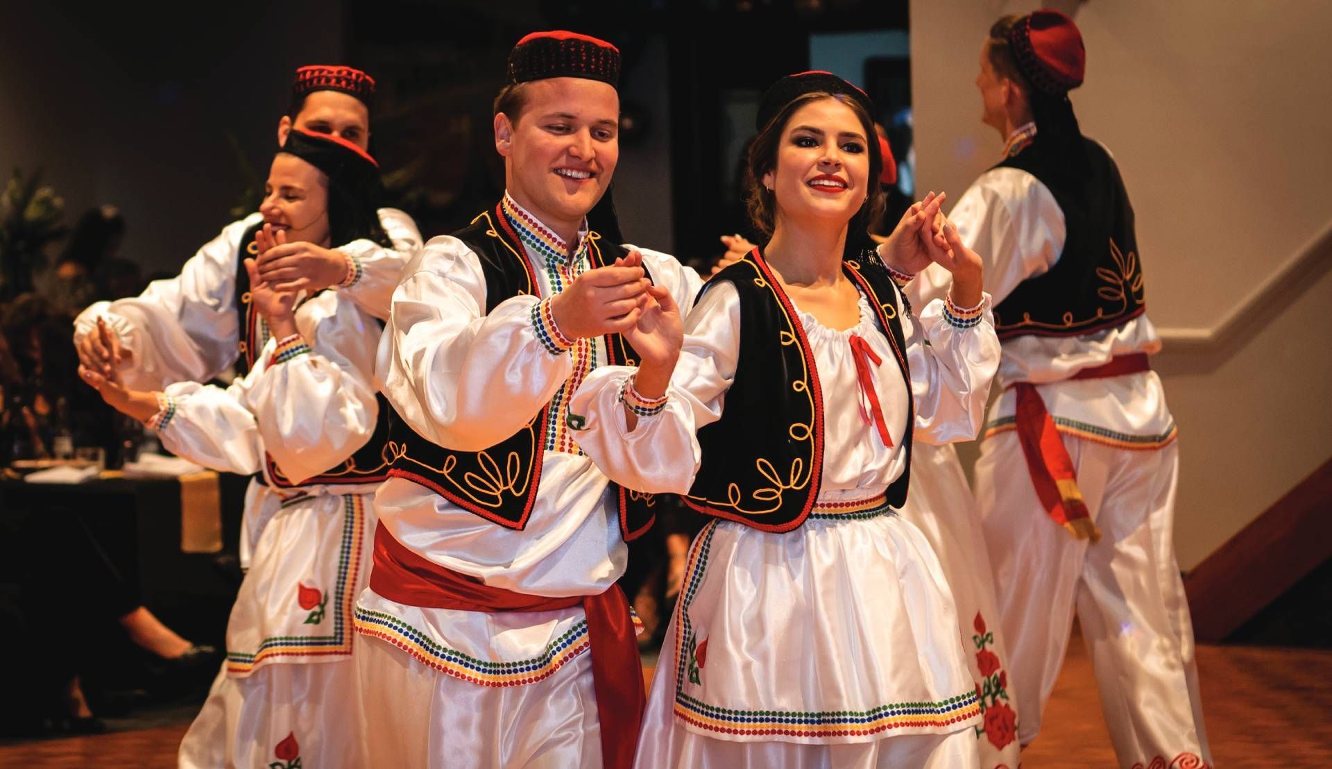 Traditional folk dancers in white and red costumes performing on stage