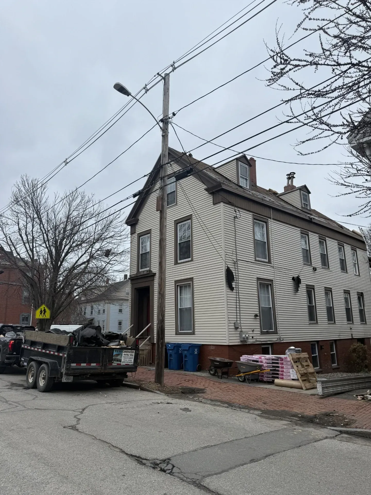Damaged two-story house on a cracked street with a truck and utility poles nearby