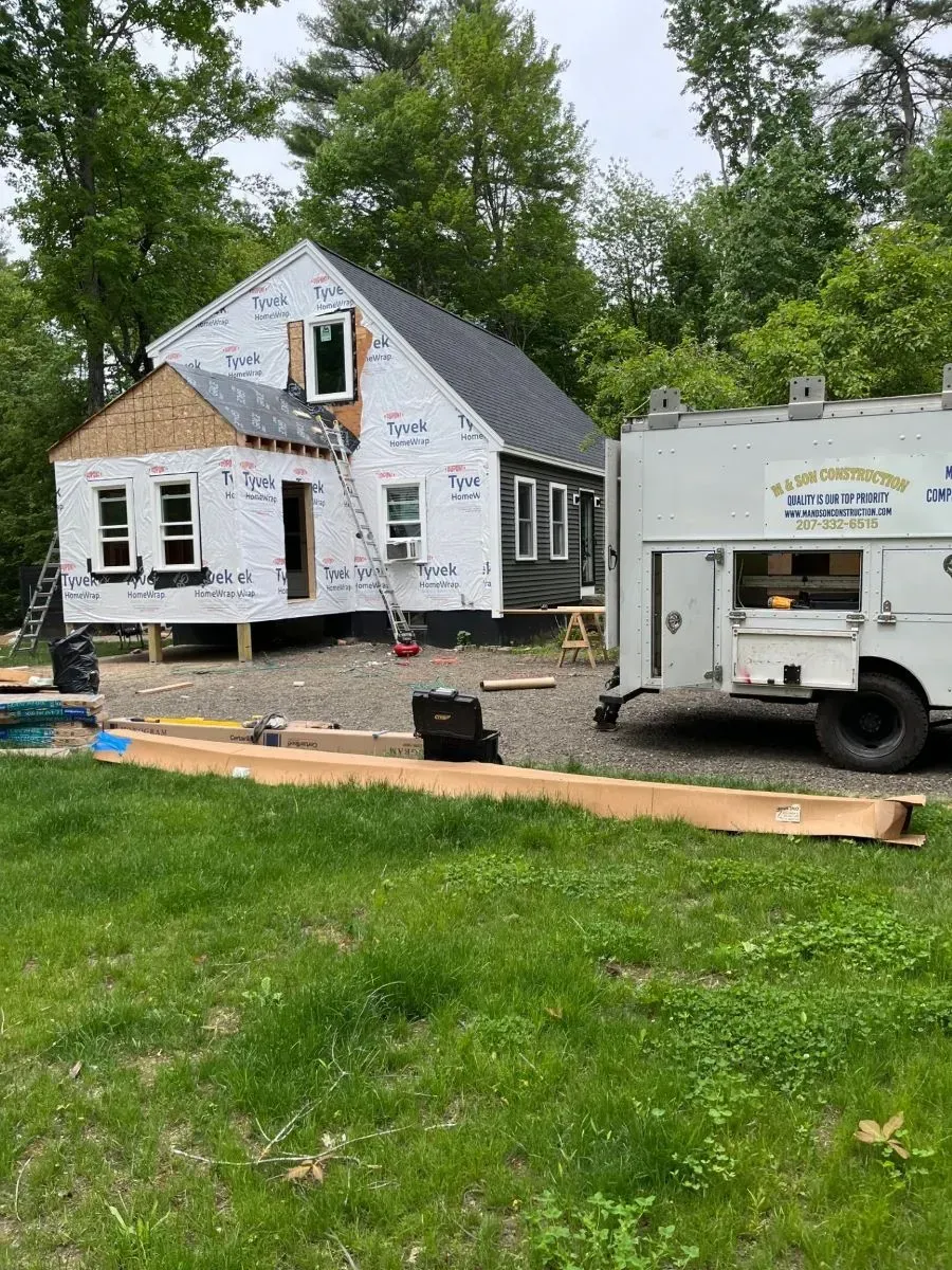 A white truck is parked in front of a house under construction.