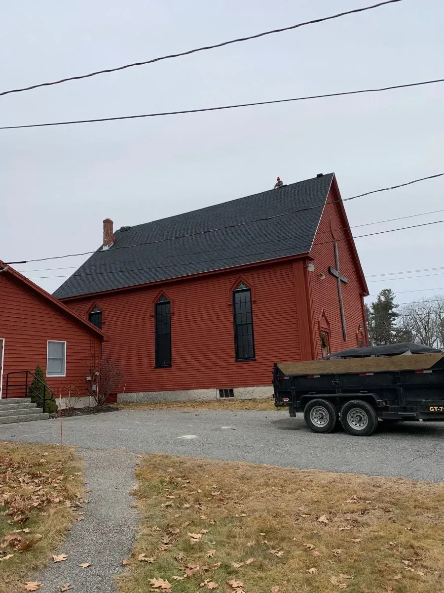 A dump truck is parked in front of a red building.