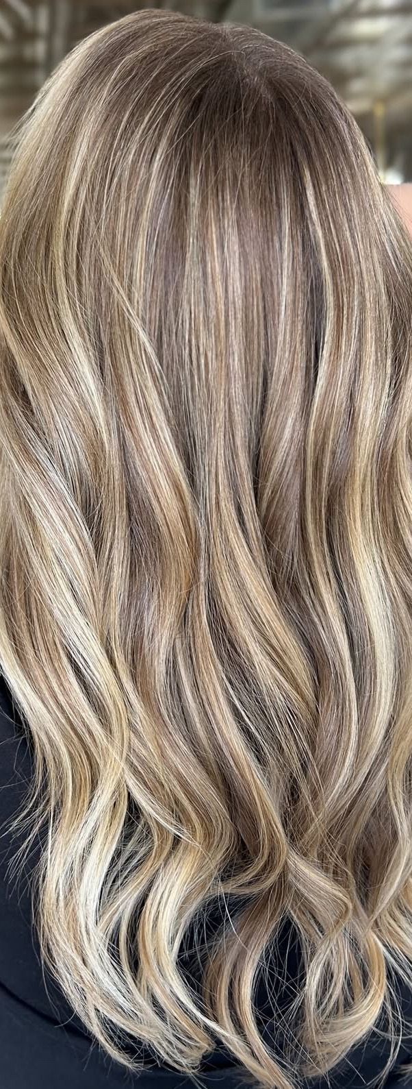 Woman's wavy, highlighted hair with shades of blonde and brown.