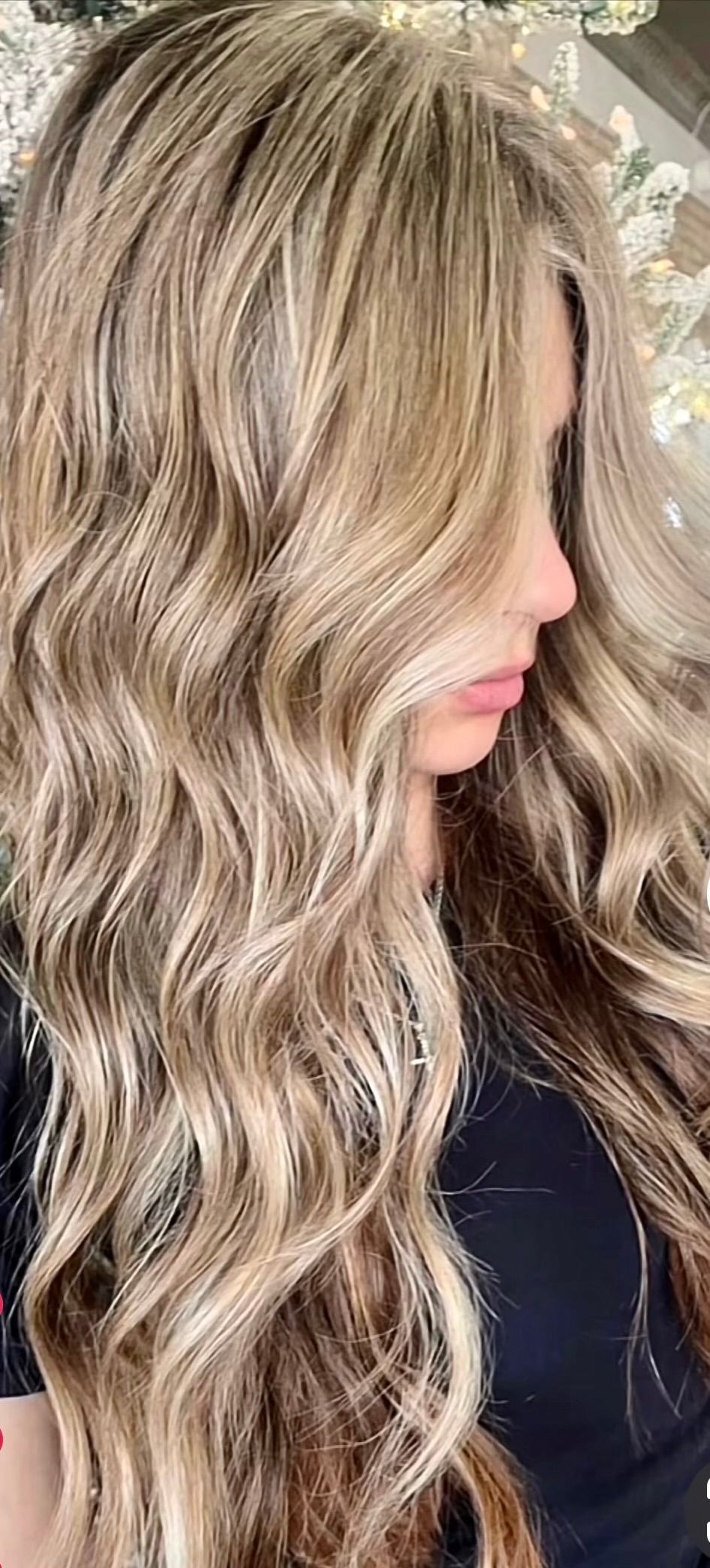 Woman with long, wavy blonde hair; profile view, wearing a dark top.