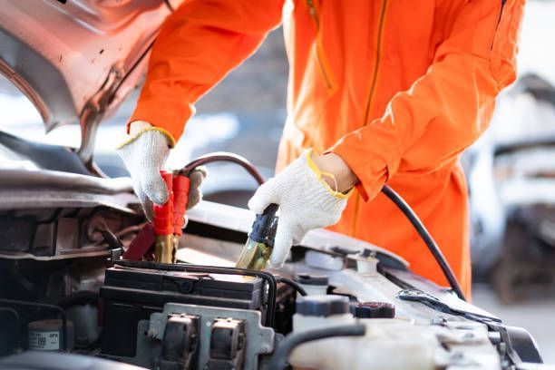 Mobile mechanic connecting jumper cables to a car battery for emergency roadside assistance