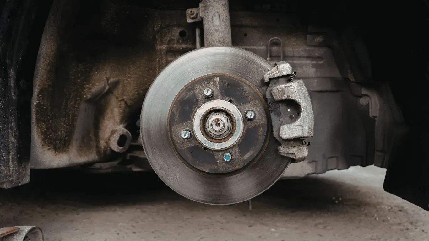 Close-up view of a car brake rotor and caliper assembly during a mobile brake repair service.
